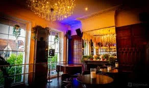 Elegant lounge with large windows, chandeliers, and colorful ambient lighting.