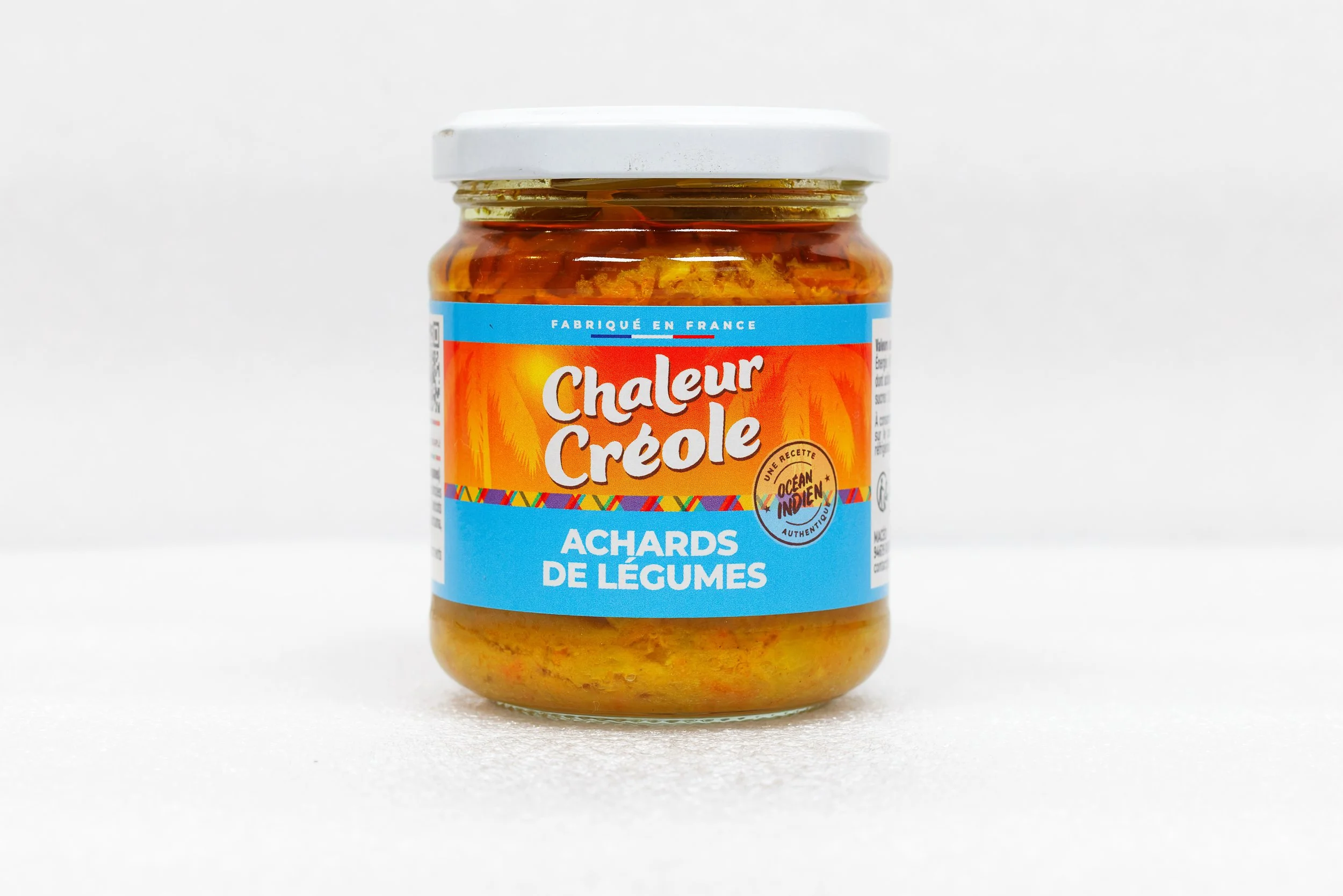 Pot de achards de légumes, étiquette en français avec inscription "Chaleur Créole" et description de saveurs exotiques.