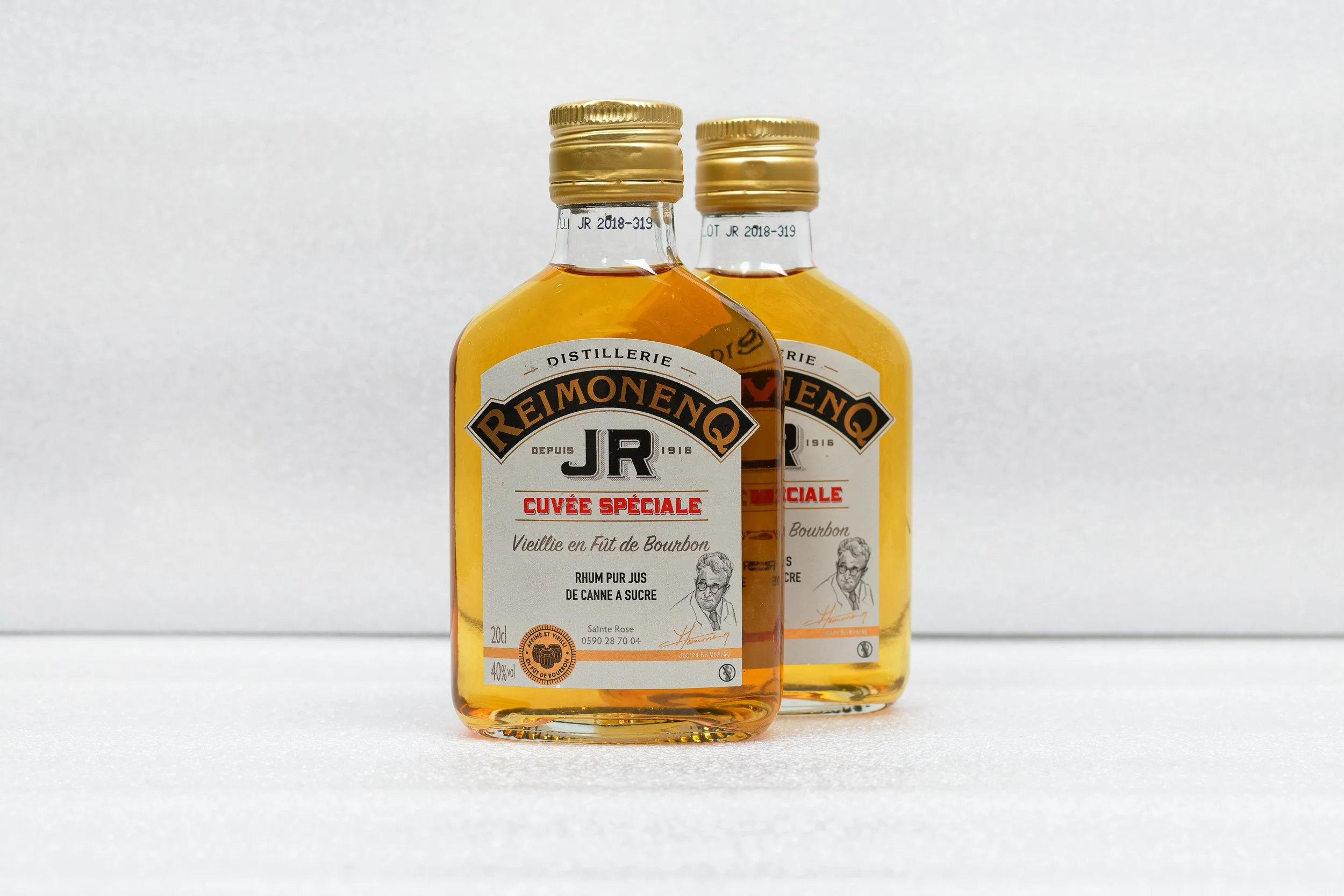 Deux bouteilles de rhum Reimonengo JR avec des étiquettes en français, contenant du rhum vieilli en Fût de Bourbon. La photo est prise contre un fond blanc.