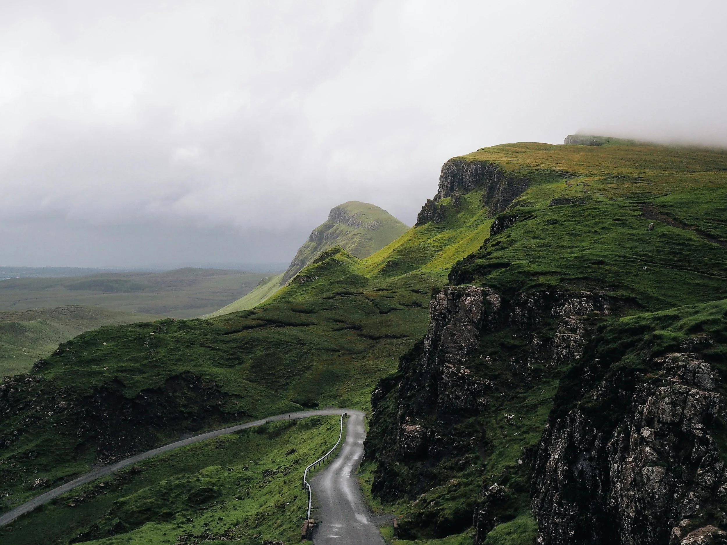 A winding road through Scottish green mountains with fog-covered peaks in the background. Your cleaning journey starts here.