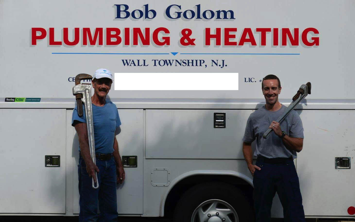 Two men standing in front of a plumbing truck with the sign 'Bob Golom Plumbing & Heating' in Wall Township, N.J. Both are holding large wrenches, one with a pipe wrench over the shoulder and the other with a regular wrench.