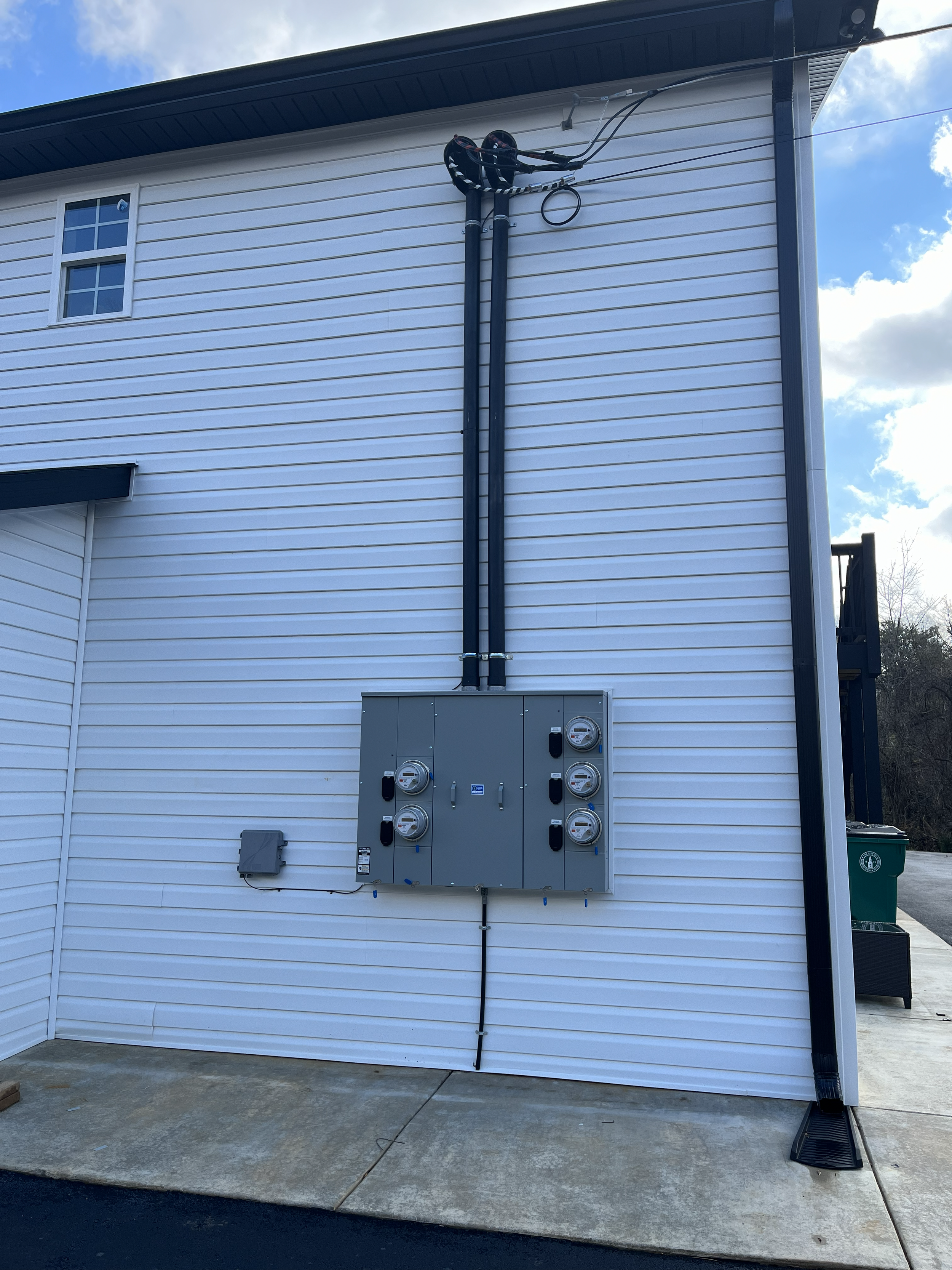 External view of a white house showing electrical meters and conduit mounted on the exterior wall.
