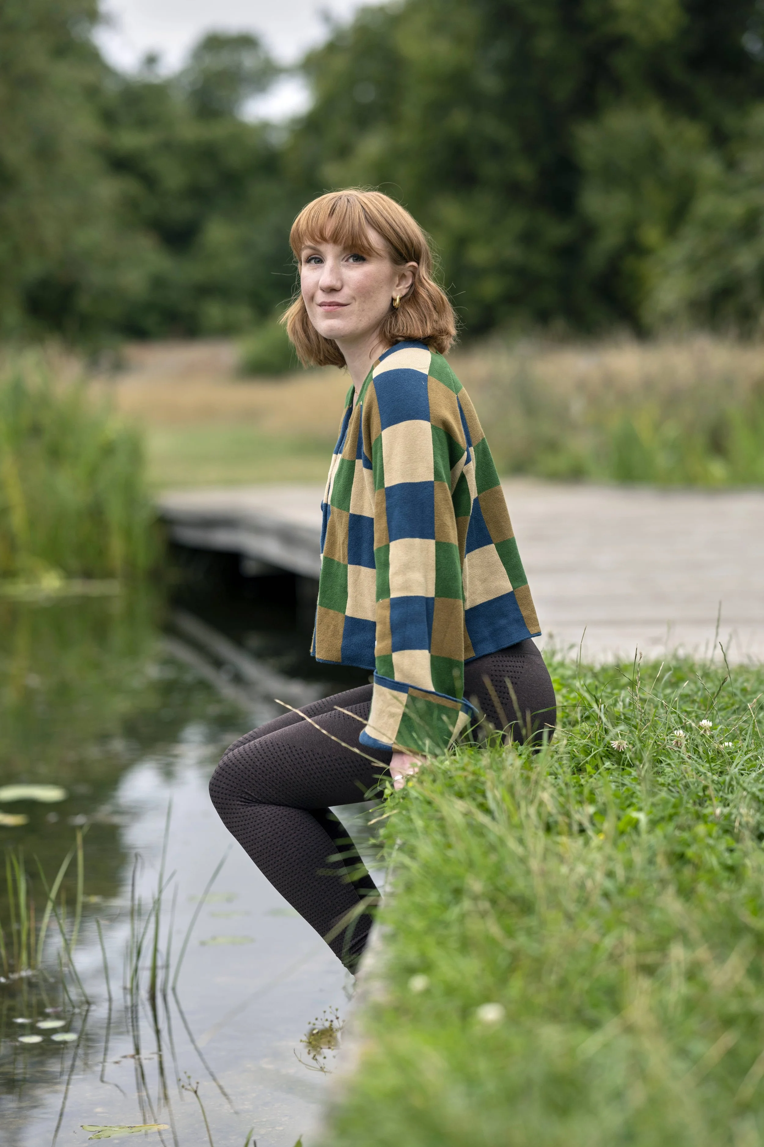 Portrait photograph to introduce Saffron Walden Yoga teacher Vicky from Pause Breath Flow. Sitting in meditation by a pond in Cambridgeshire near Saffron Walden.