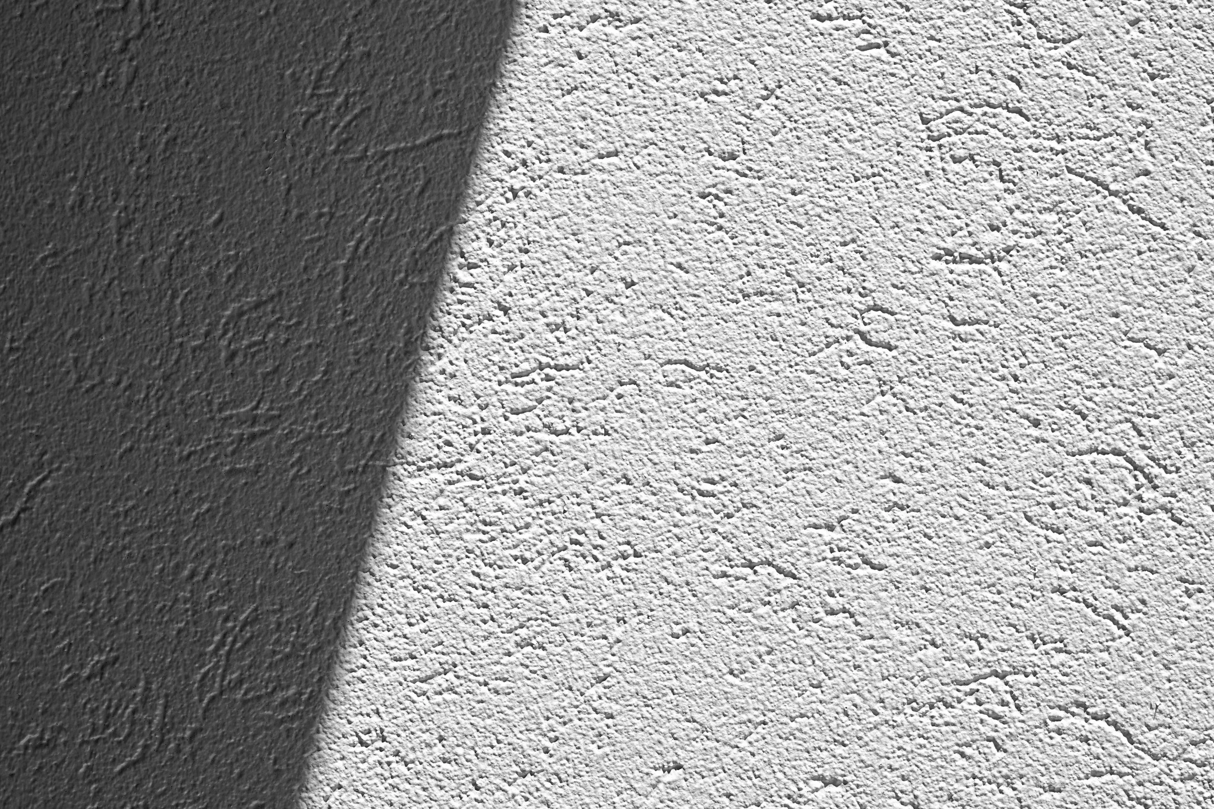 Close-up of a textured wall with a shadow cast on the left side.