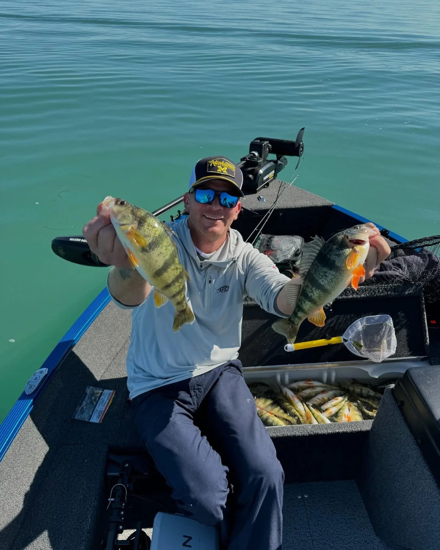 Captain Lucas holding two Lake St. Clair perch during a guided fishing charter.