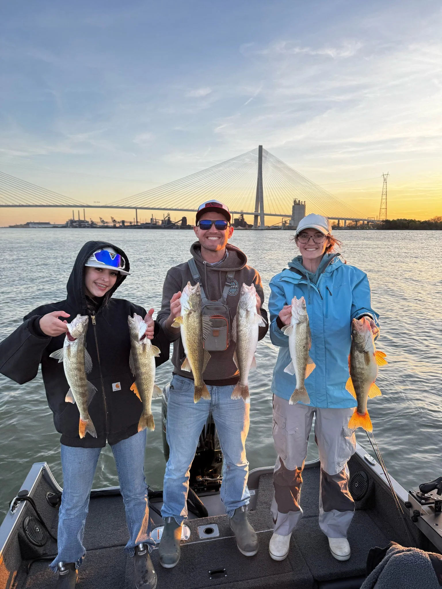 Family holding Detroit River walleye aboard a guided fishing charter at sunrise in Southeast Michigan.