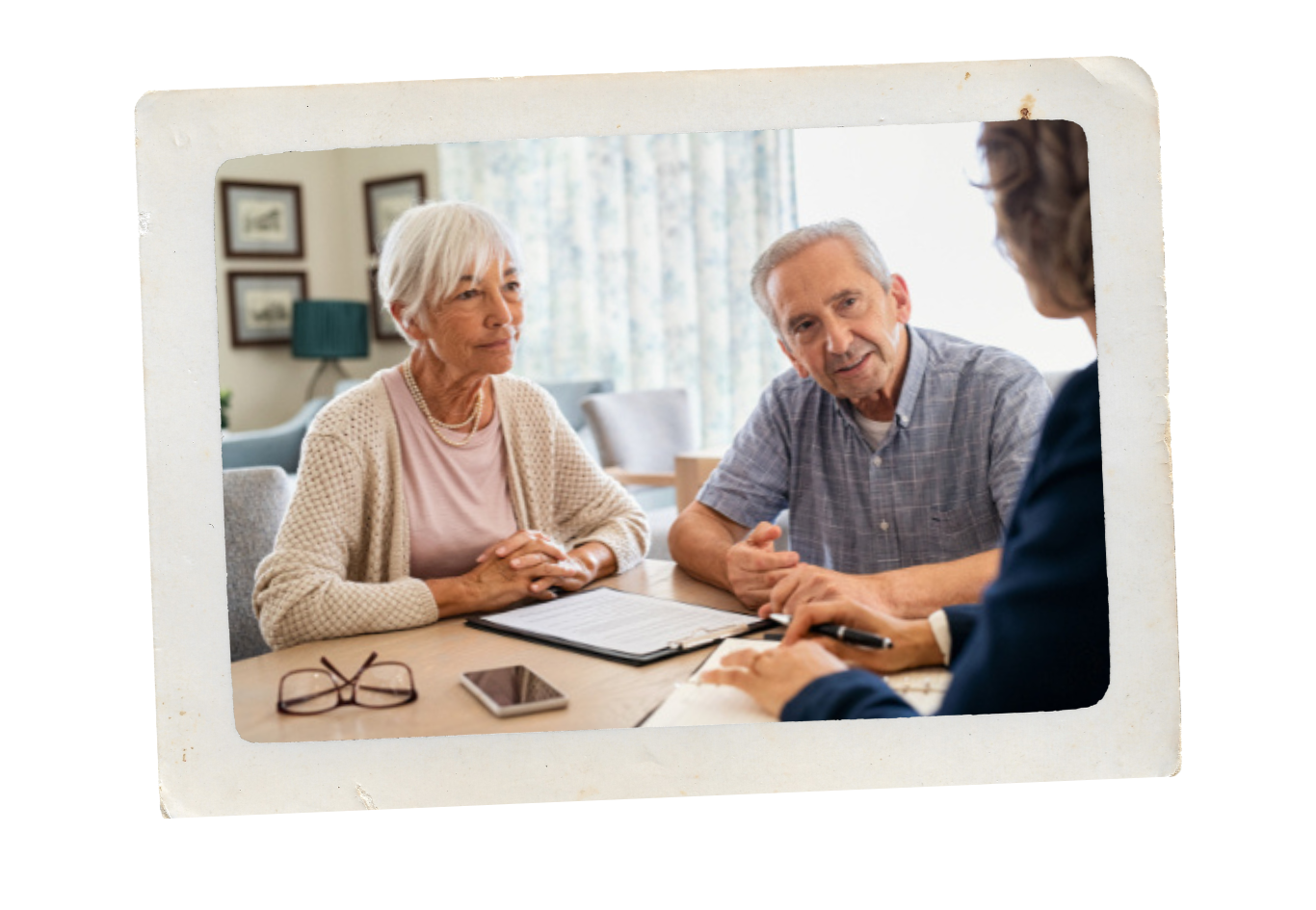 An elderly couple sitting at a table with a professional, possibly a financial advisor, discussing documents.