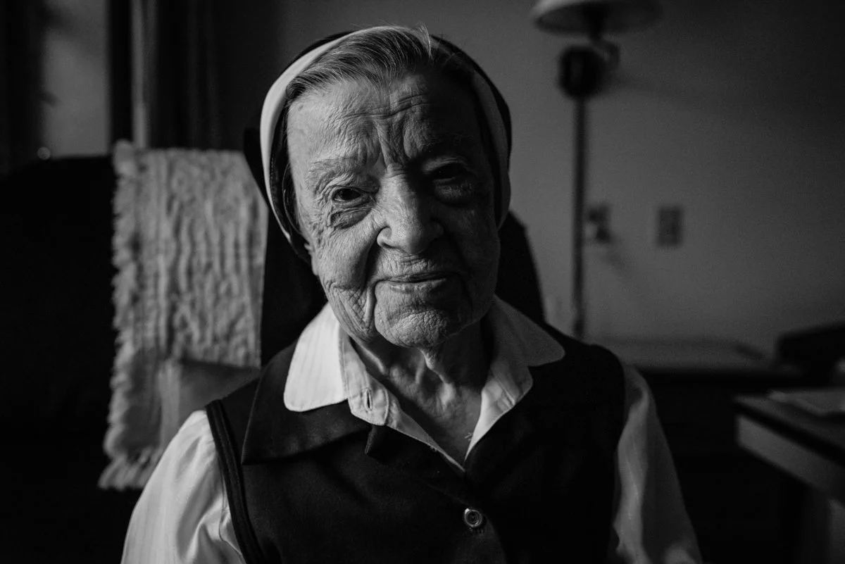 Natural light portrait of a senior nun smiling in black and white. humanitarian project 