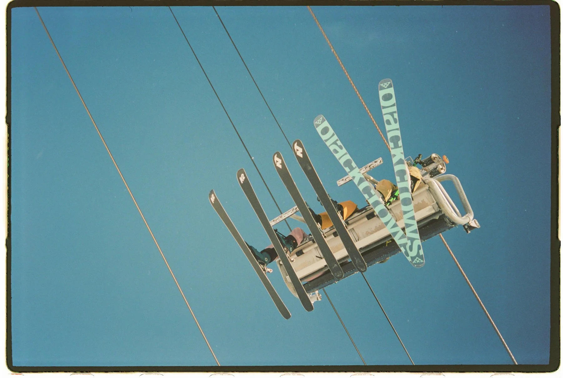 ski resort skiers on chairlift bottom of skis shot on 35mm film 