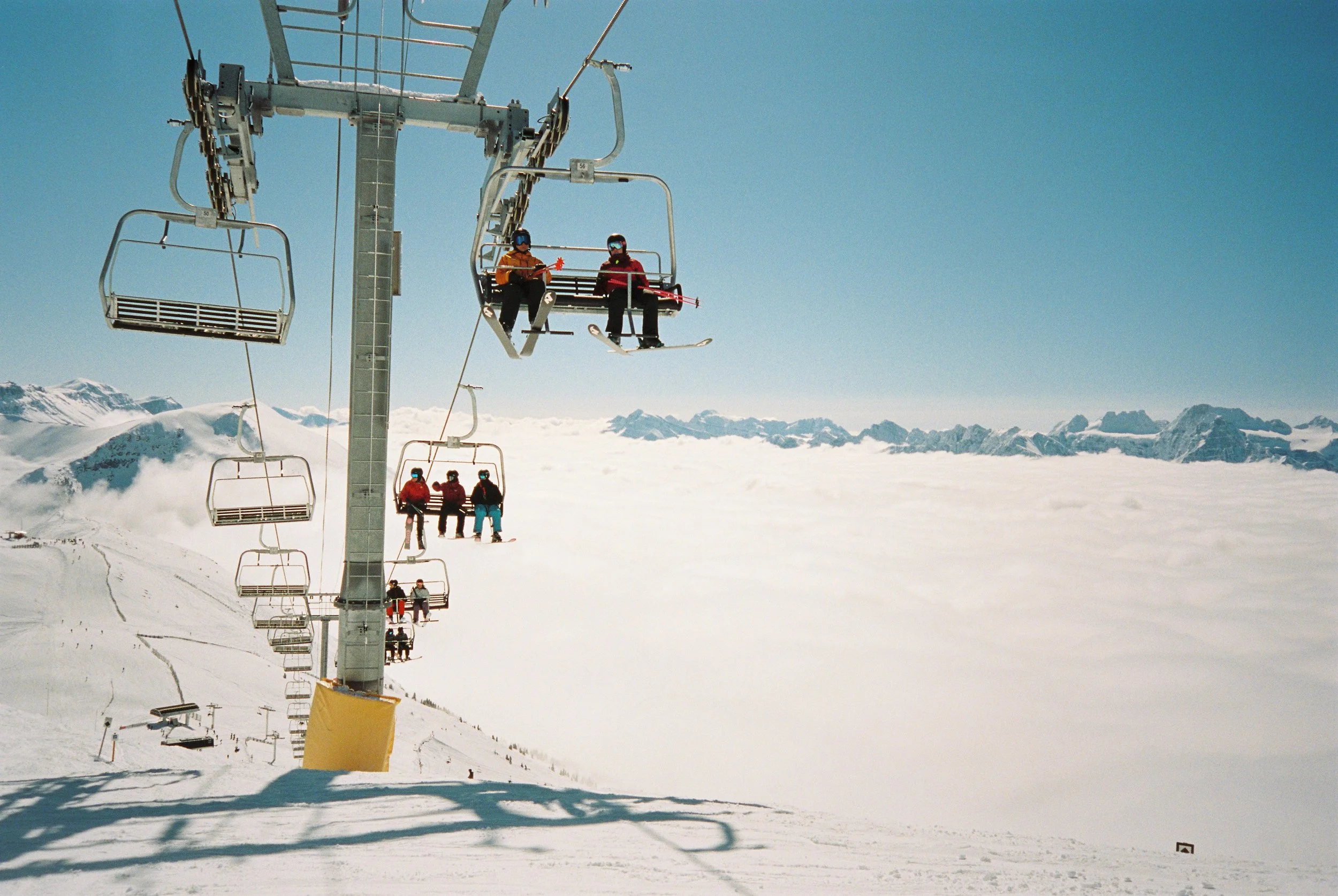 People on a chair lift with a cloud inversion in Banff Canada blue sky vintage feel 35 mm film ski culture 