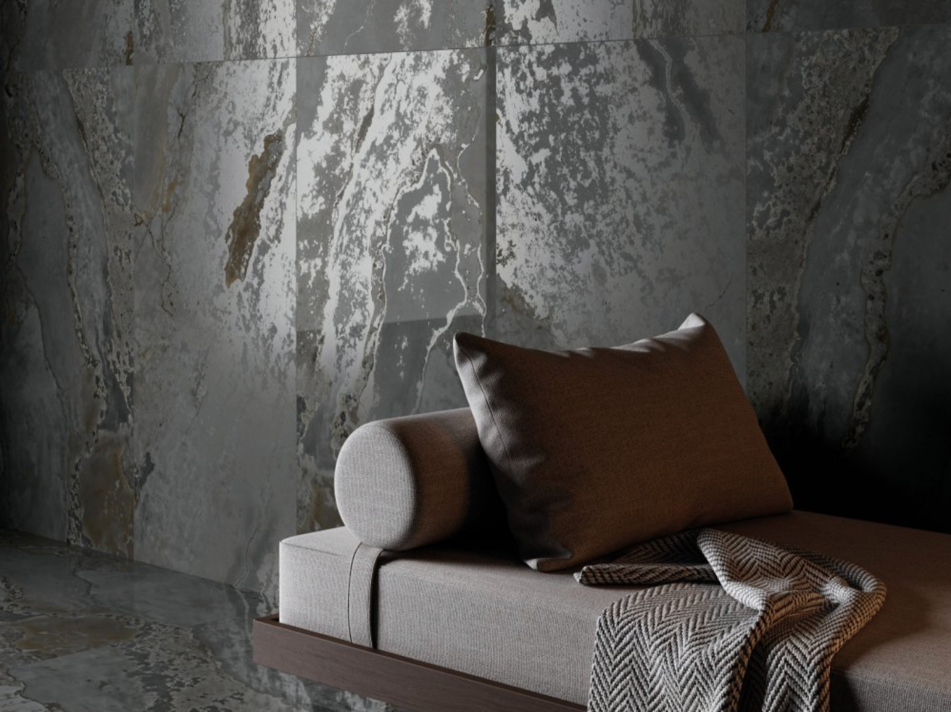 A modern living room corner with a beige sofa, dark brown cushion, and a patterned blanket, against a textured gray stone wall.