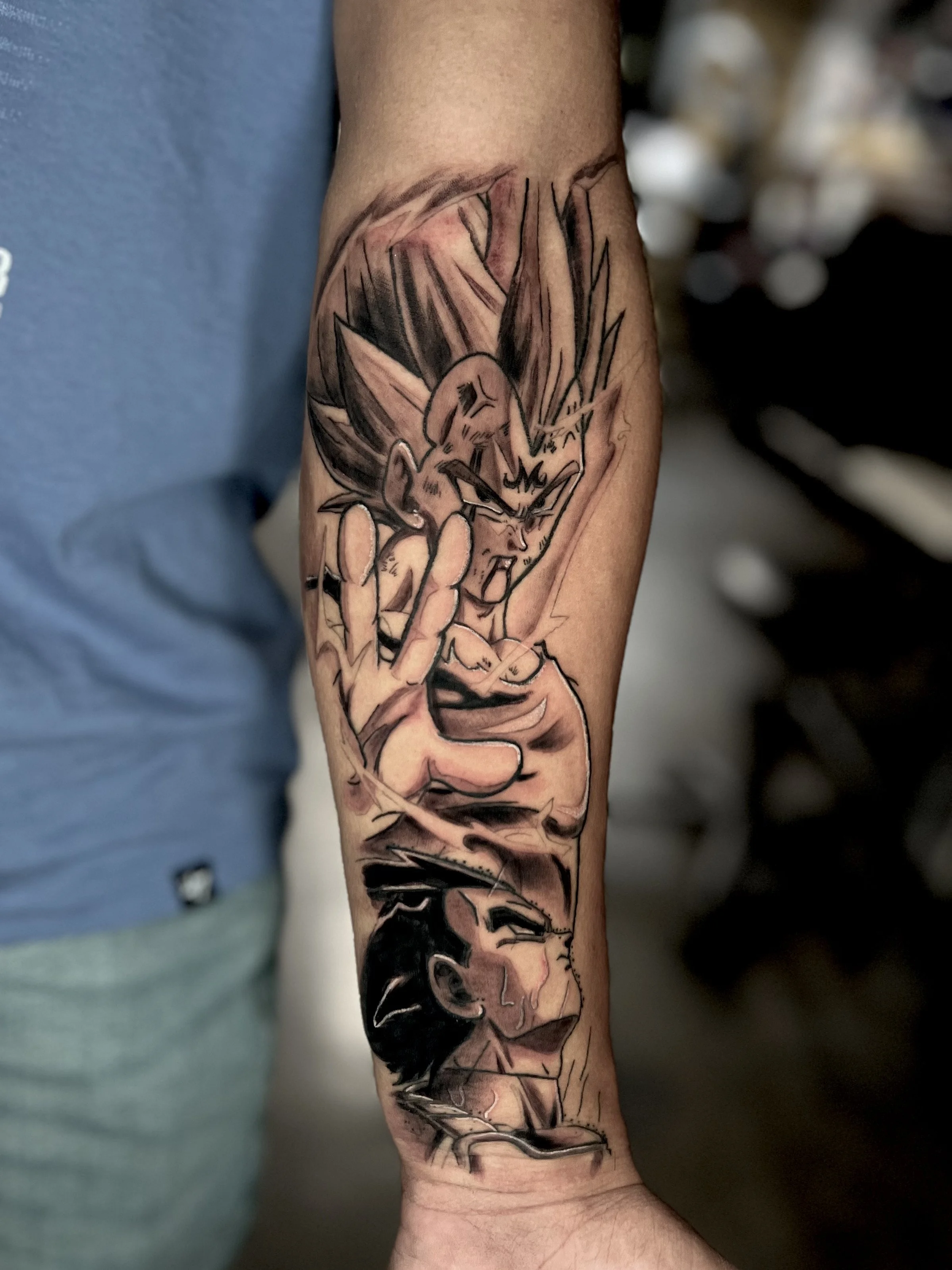 Tattoo of Vegeta from Dragon Ball Z on a person's forearm. Vegeta has spiky hair, an angry expression, and is making a hand gesture with his fingers.