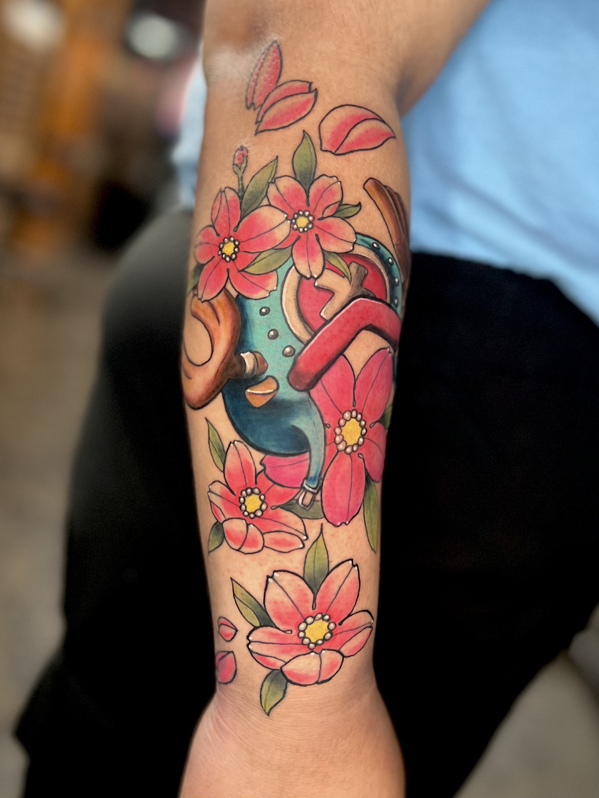 Colorful tattoo of a clock with flowers on a person's forearm.