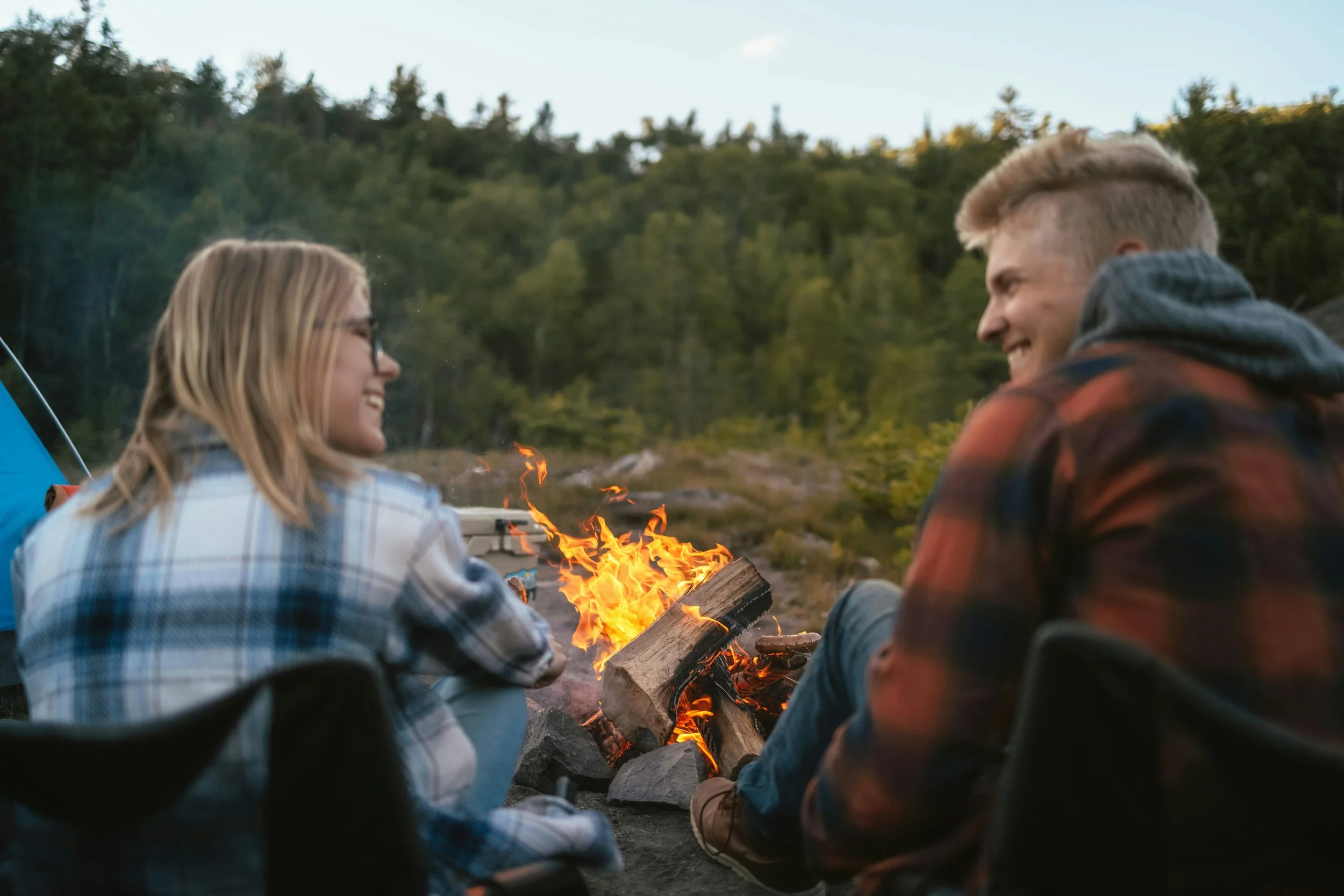 happy couple sitting by a campfire