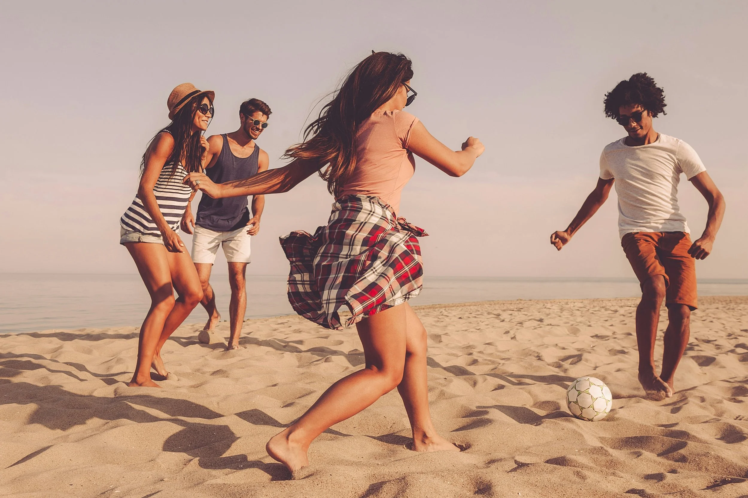 group of people playing soccer on a beach