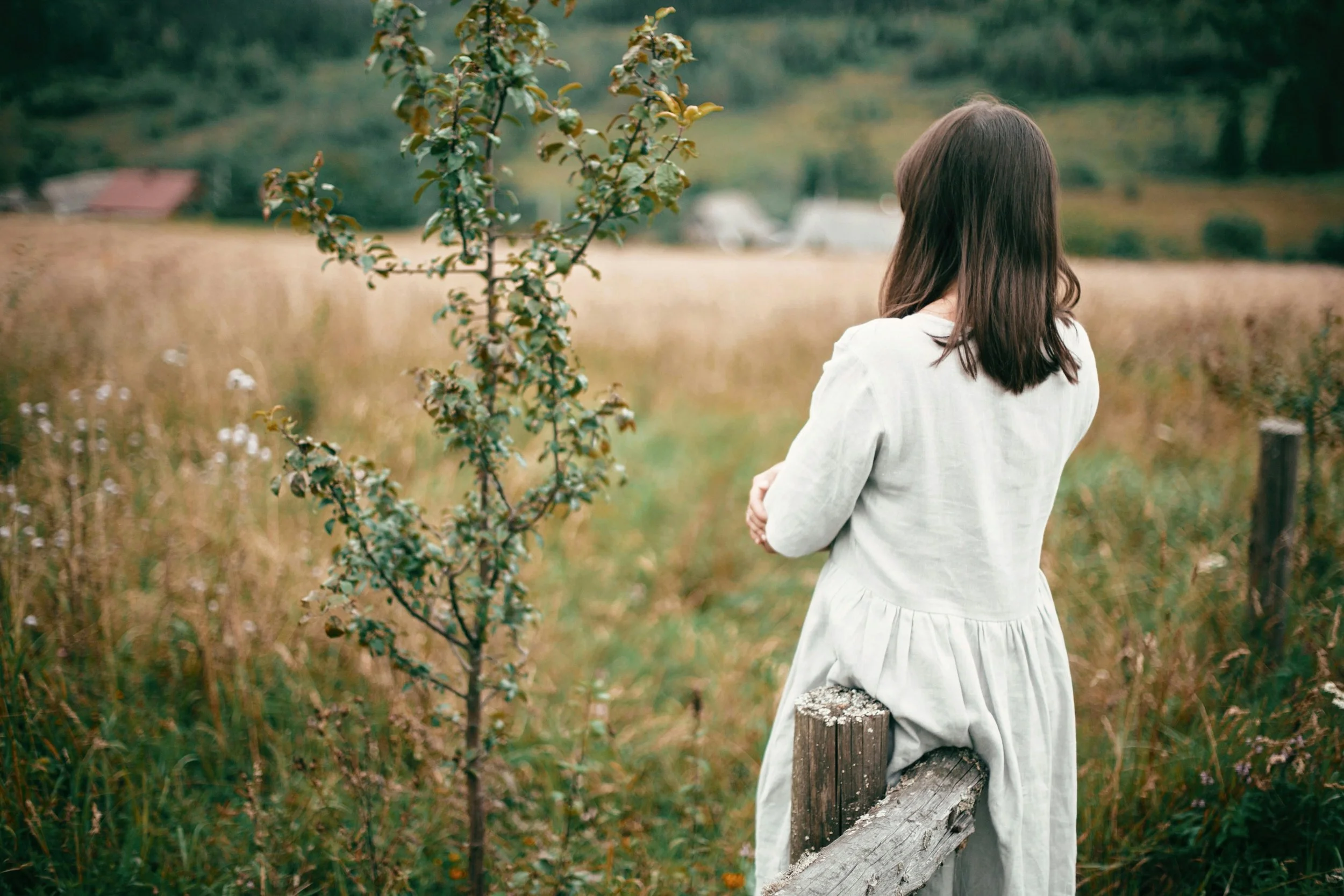 woman leaning against a wooden fence