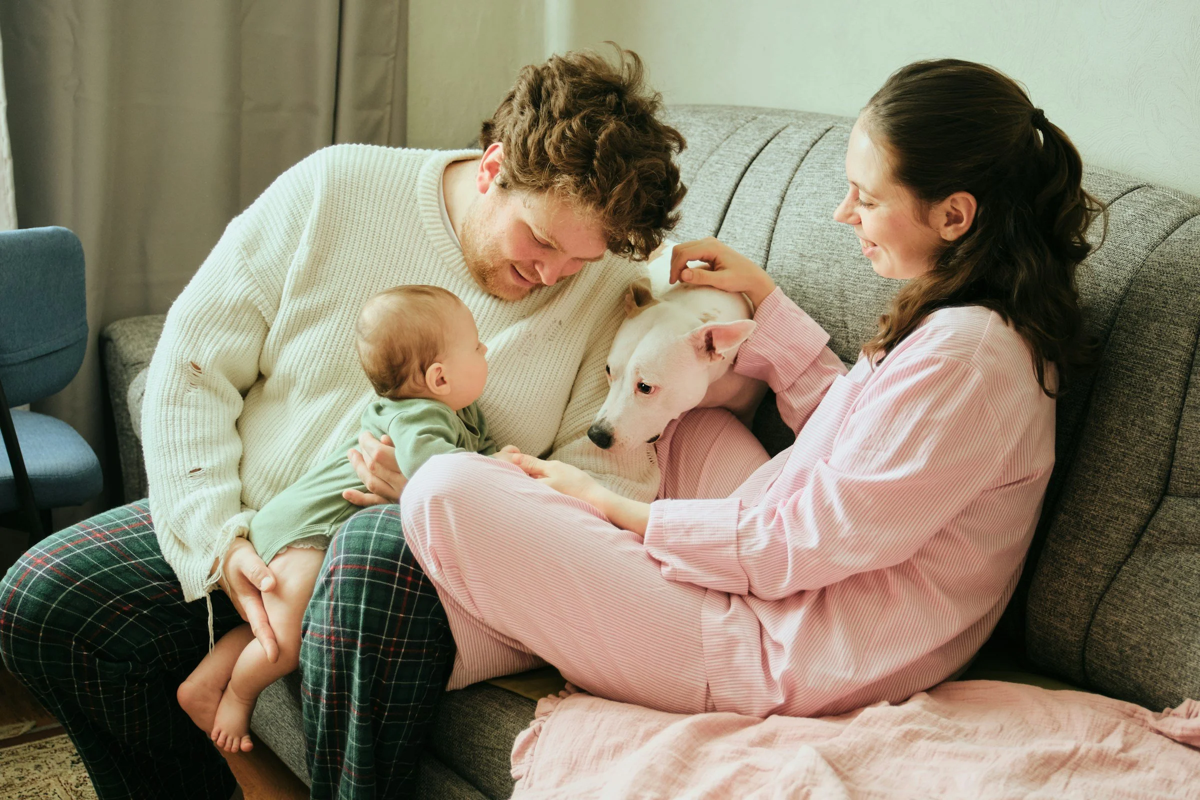 parents on a couch with baby and a dog