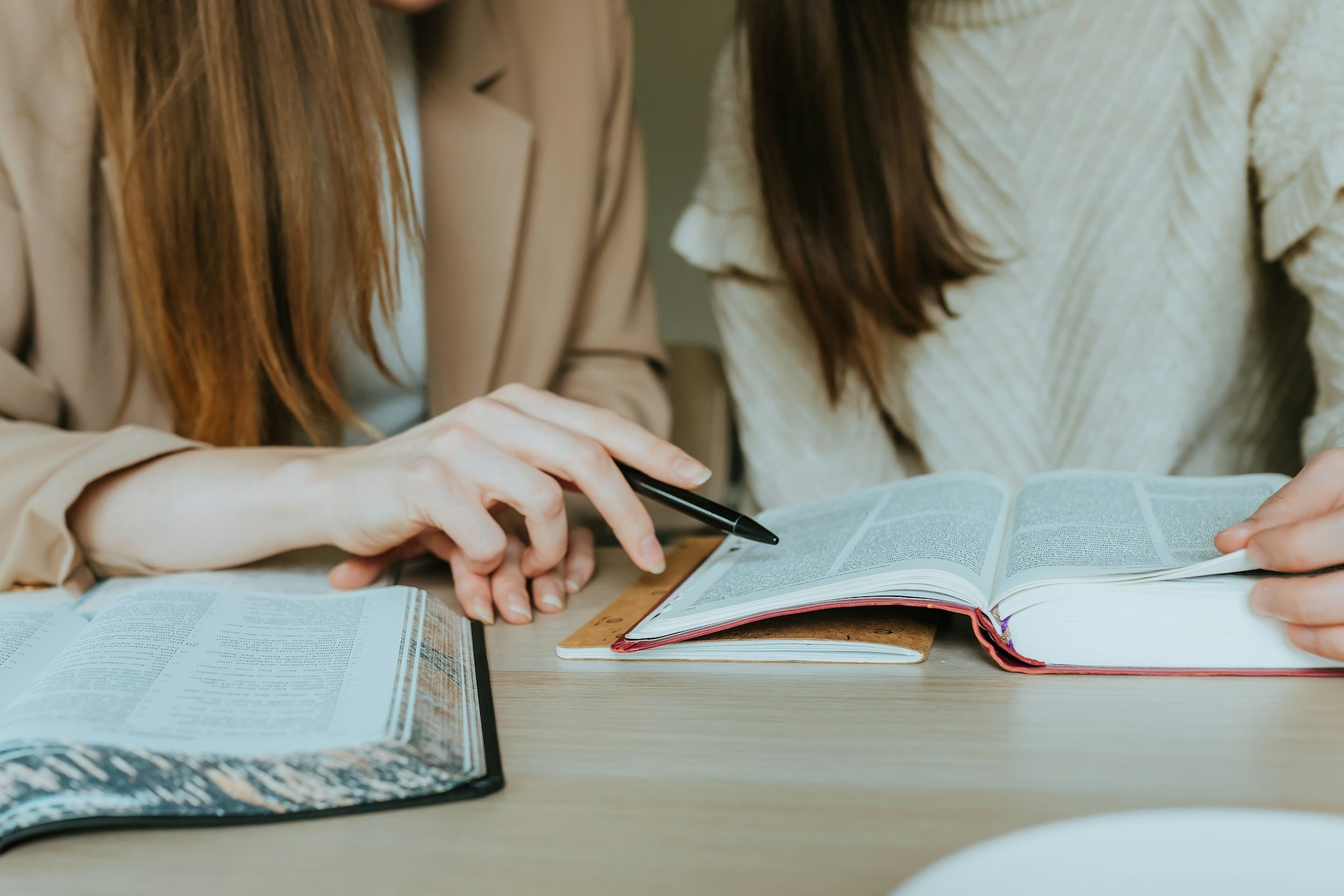Two women reading a book at a desk with improved focus and attention during ADHD treatment in Ogden Utah