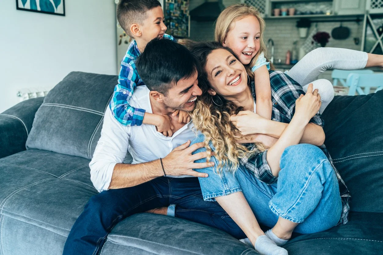 Family laughing and playing together on a couch during supportive psychiatry care in Ogden Utah