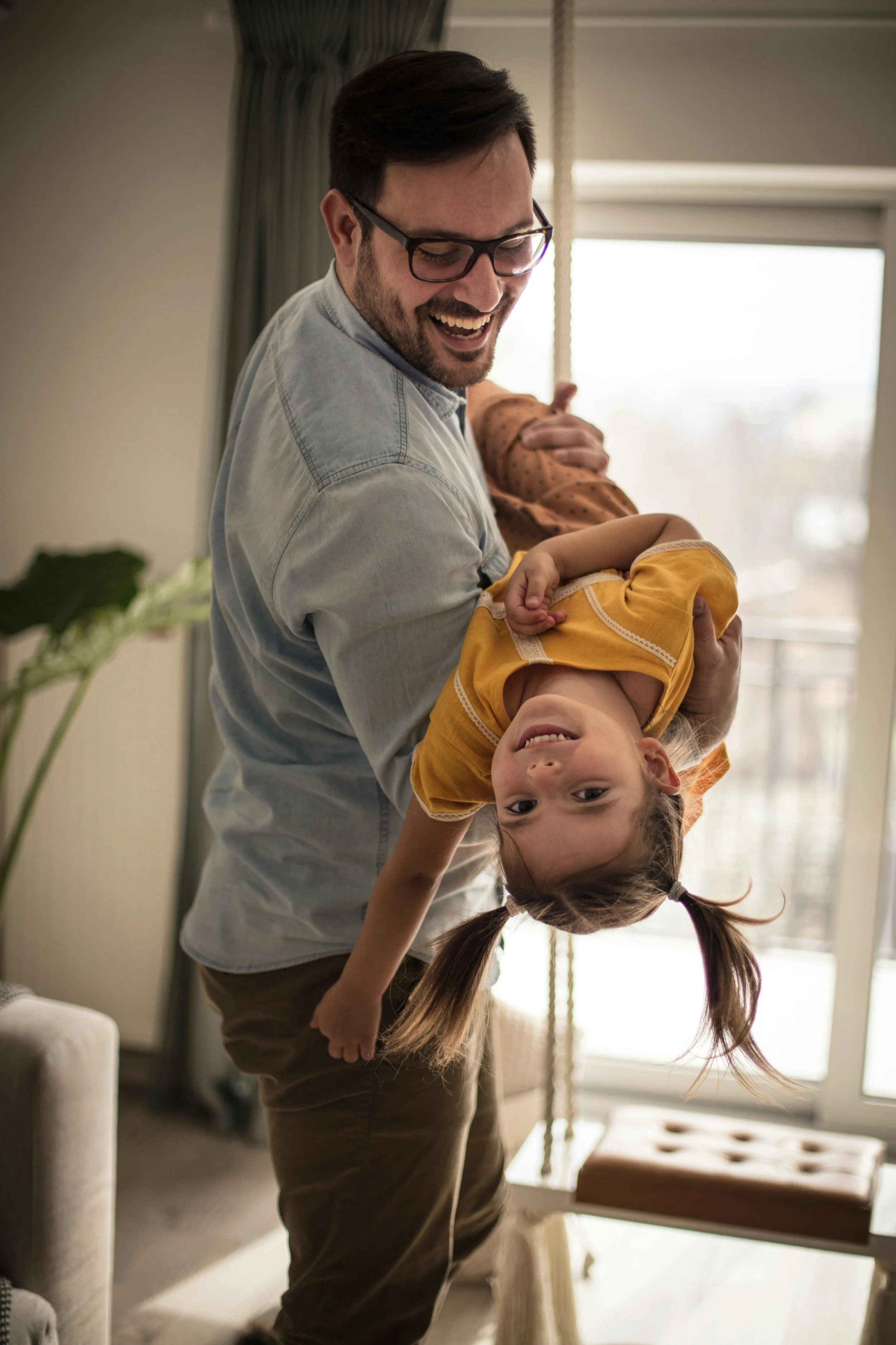 Father lifting daughter while playing together representing strong family connection and child therapy outcomes in Ogden Utah