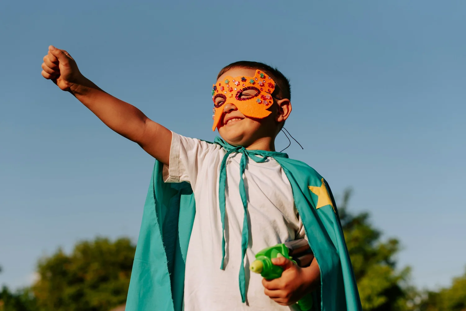 Boy in a cape and mask playing outside representing confidence after anxiety treatment in Ogden Utah