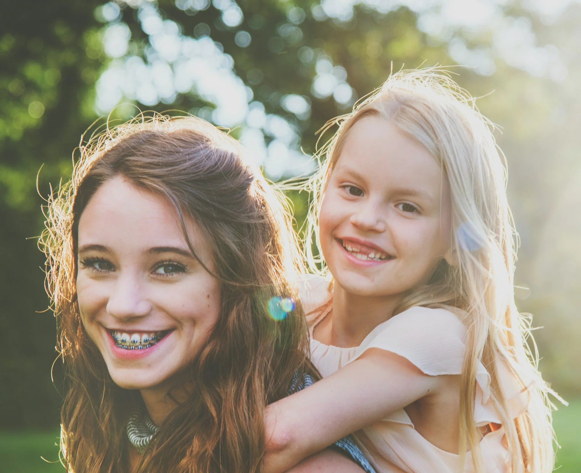 Little girl riding on her sister’s back representing confidence and connection after selective mutism treatment in Ogden Utah