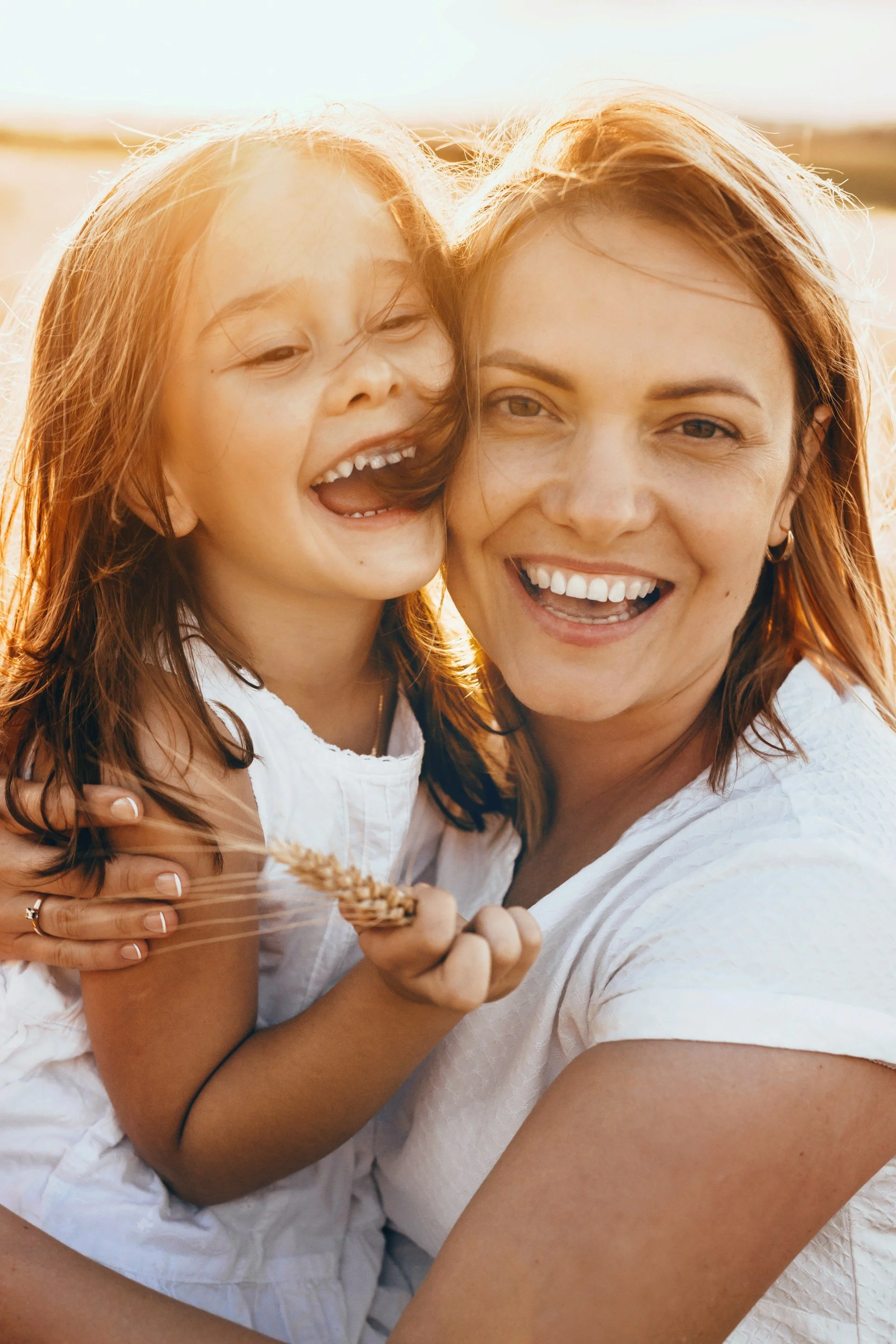 Mother and child smiling outdoors in the sun after successful family and child therapy in Ogden Utah mental health clinic