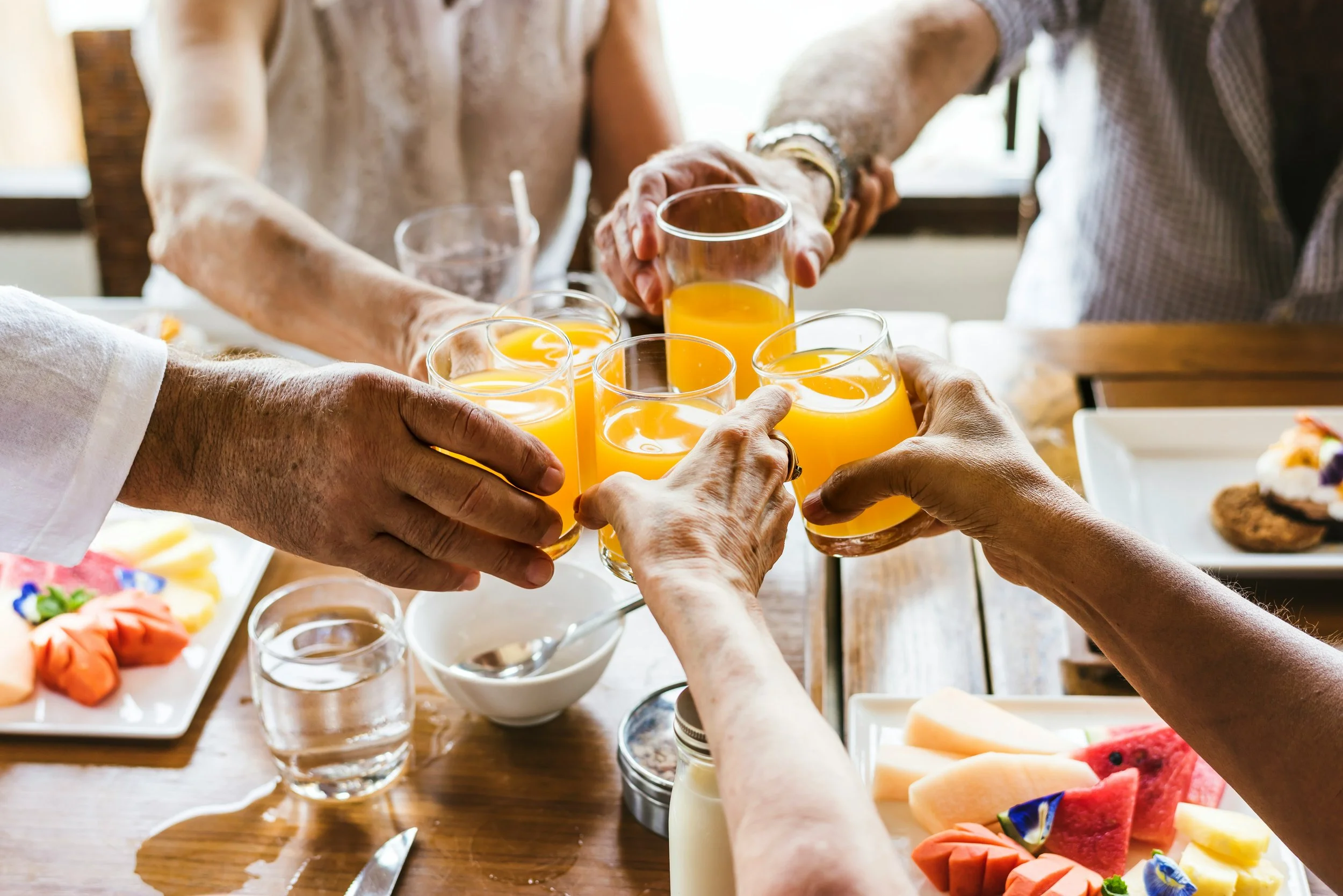 a group of people holding glasses of orange juice