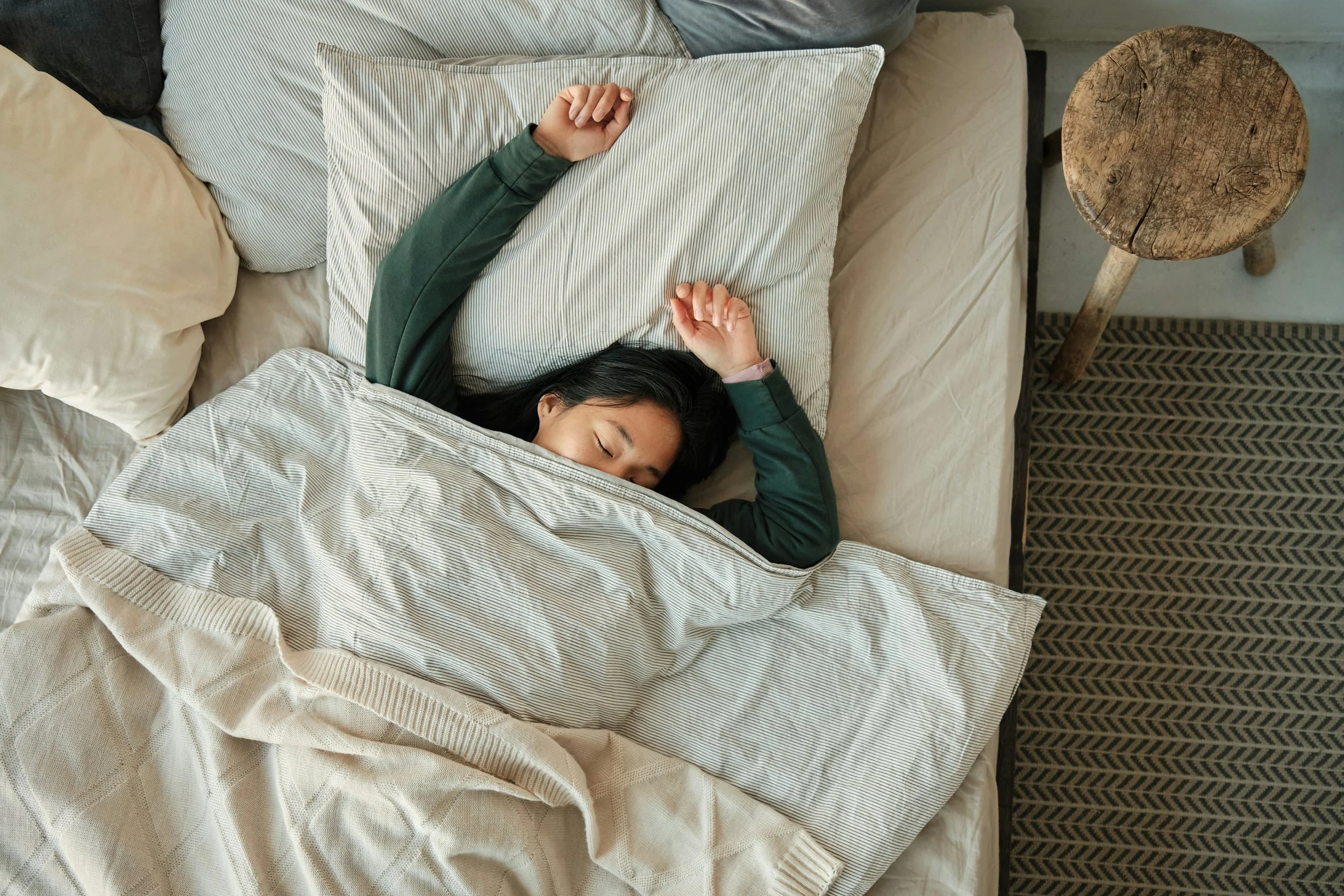 Woman sleeping soundly with her arms stretched overhead after successful insomnia treatment in Ogden Utah