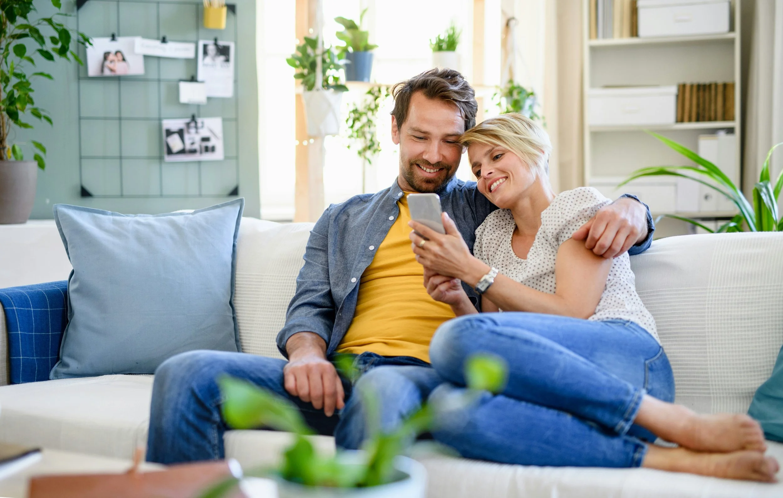 couple sitting on a couch looking at a phone