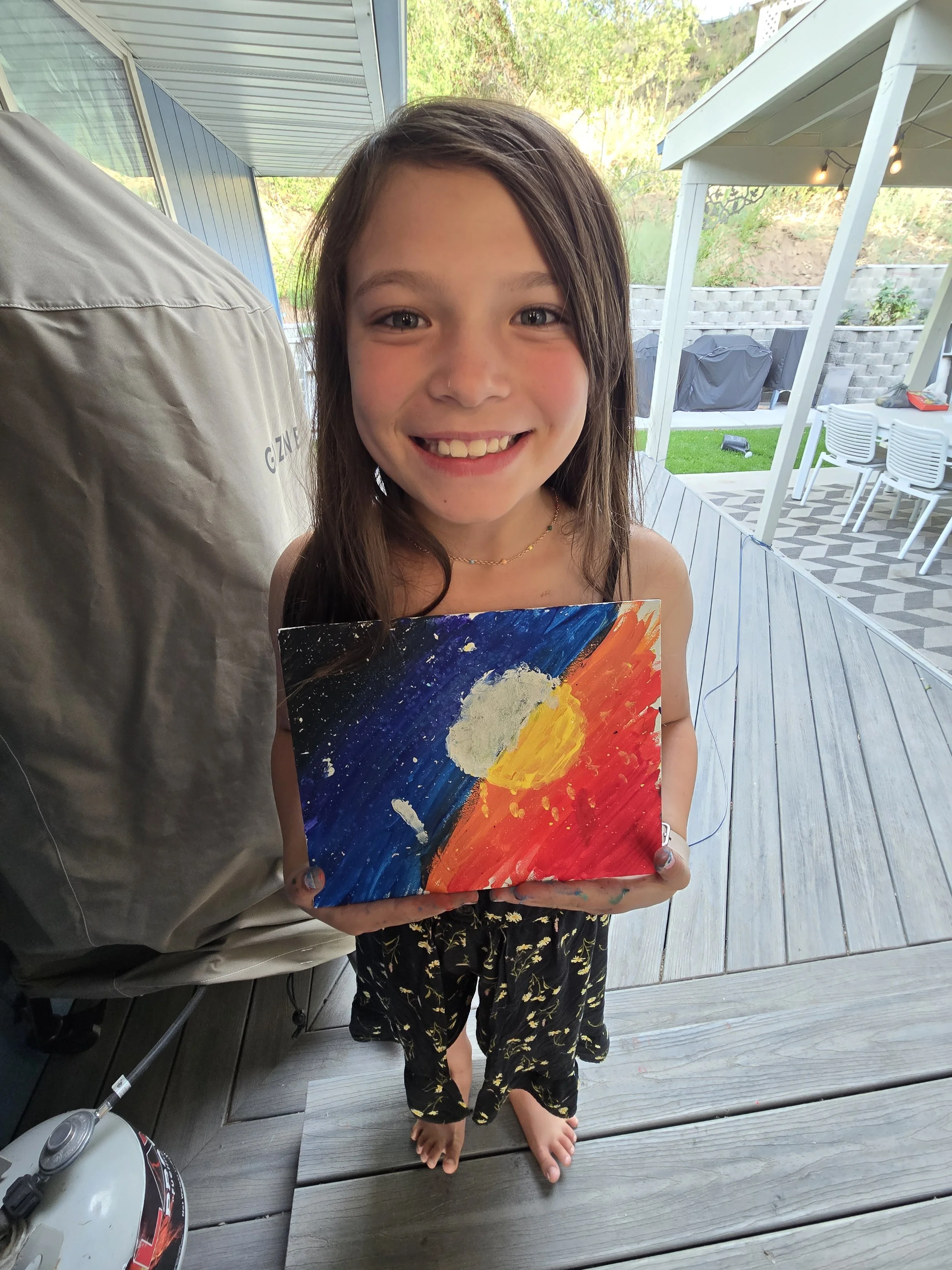 Young girl holding a painting in a yard representing healing and emotional recovery after PTSD treatment in Ogden Utah