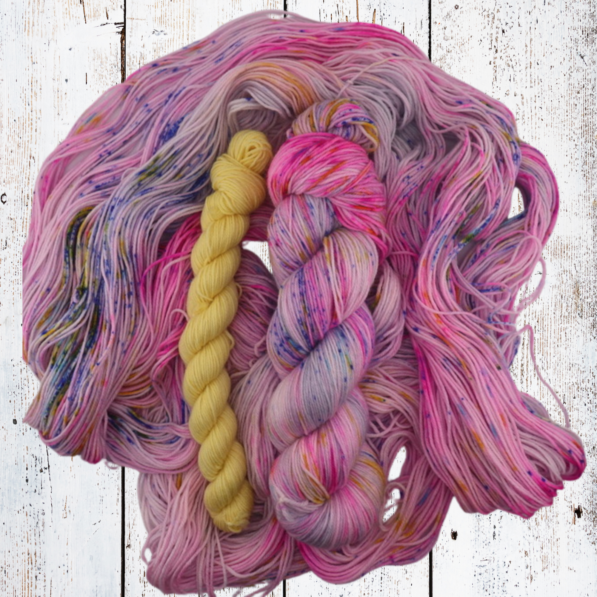 Close‑up of hand‑dyed yarn in pink, purple, blue and yellow tones, showing soft texture and subtle colour transitions for knitting and crochet projects.