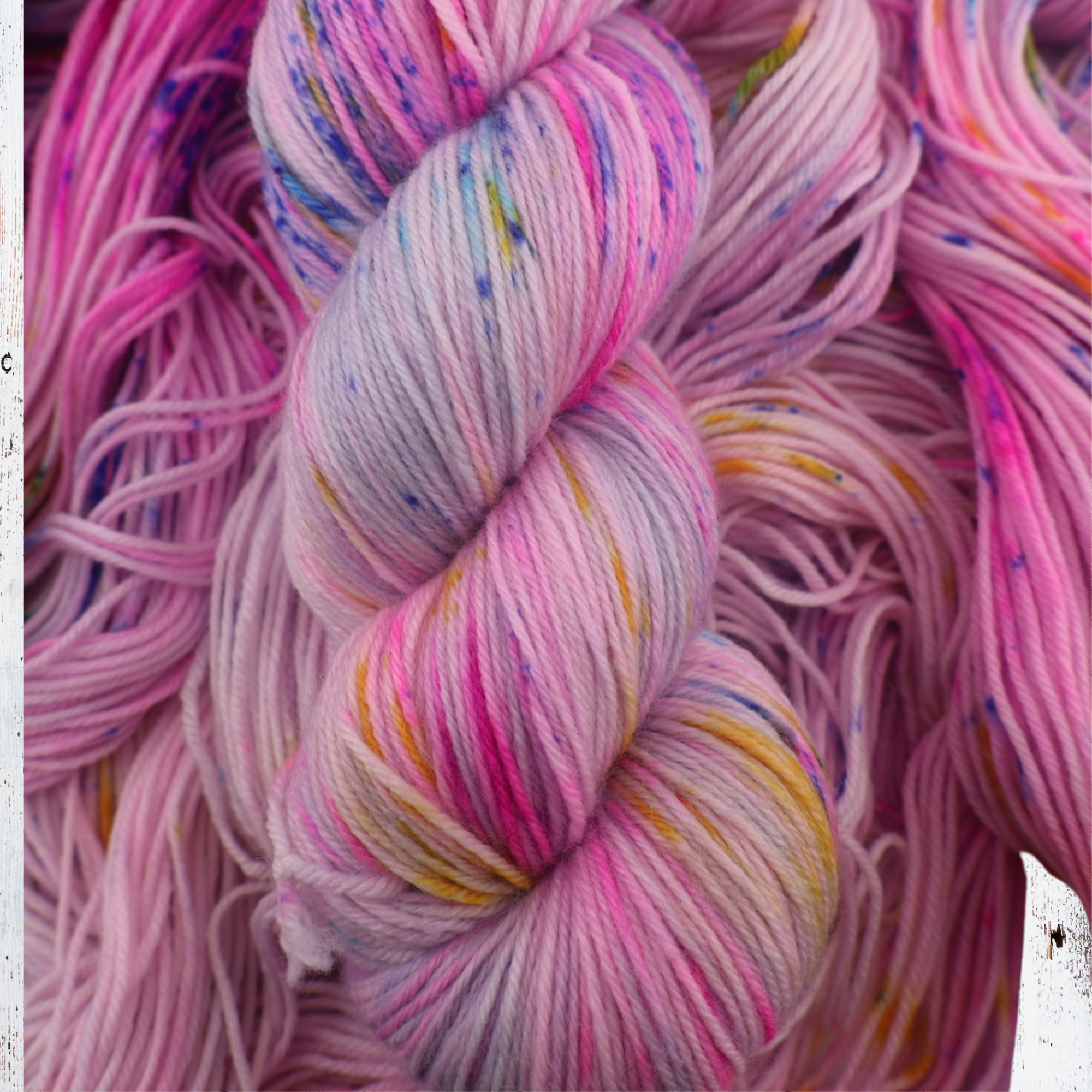 Striped knitted fabric in yellow, green, blue and purple, demonstrating how the hand‑dyed yarn blends and transitions when worked up.