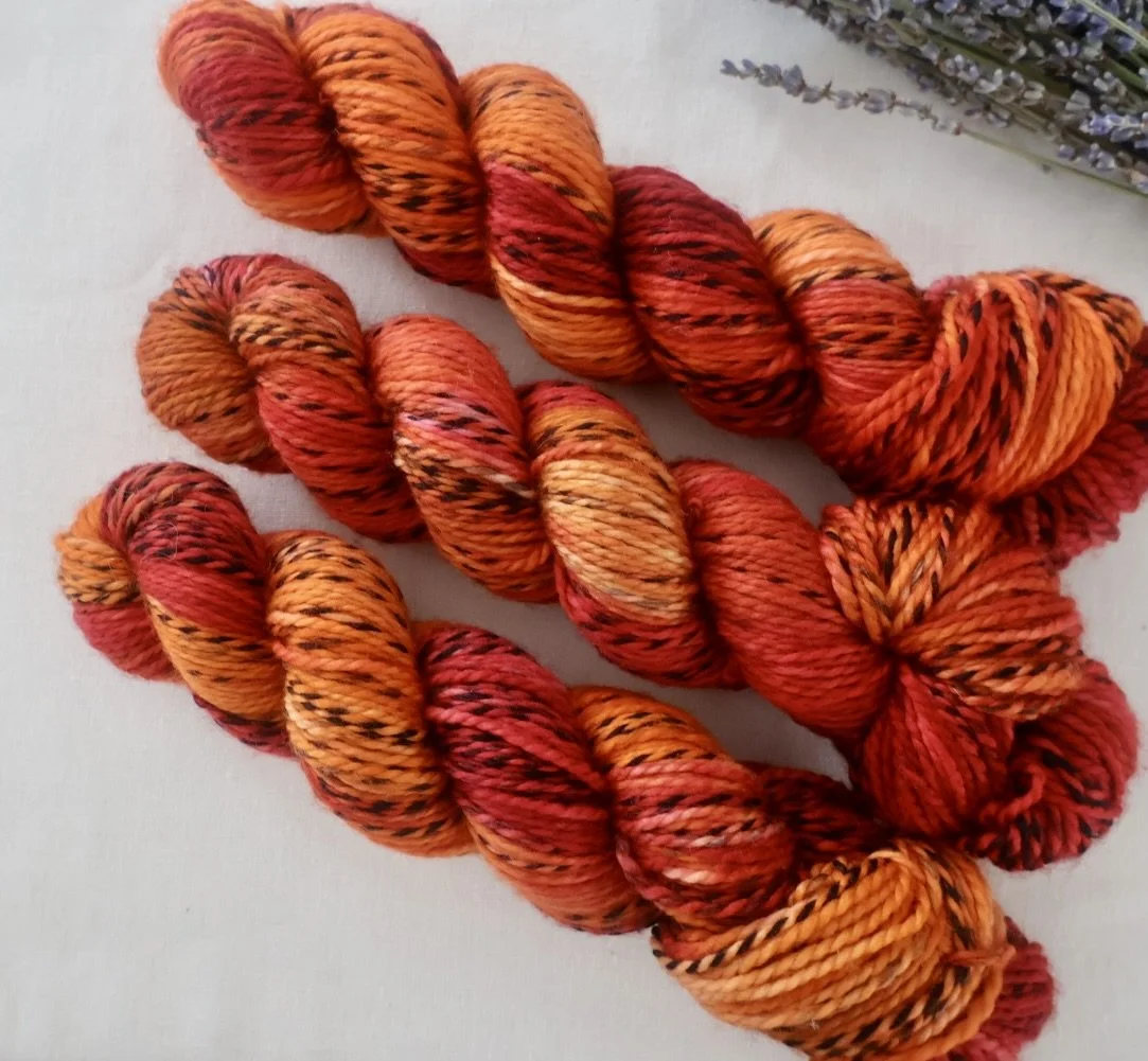 Hand‑dyed Zebra Merino DK yarn in fiery red, orange and gold tones inspired by Mary Barbour.