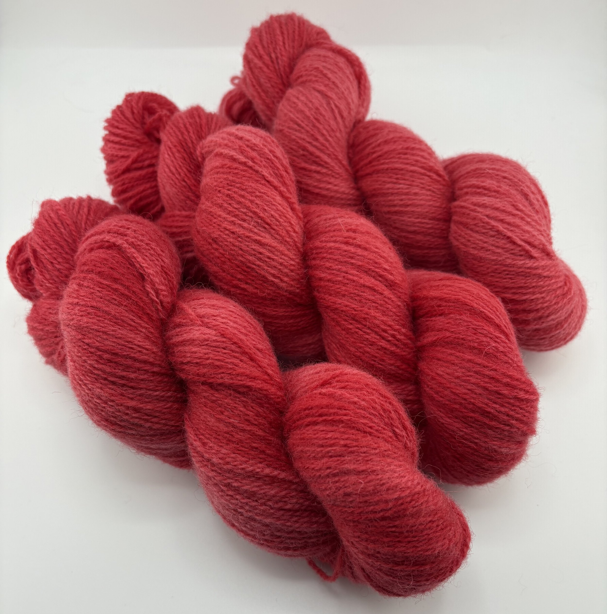 Several skeins of red yarn piled on a white surface.