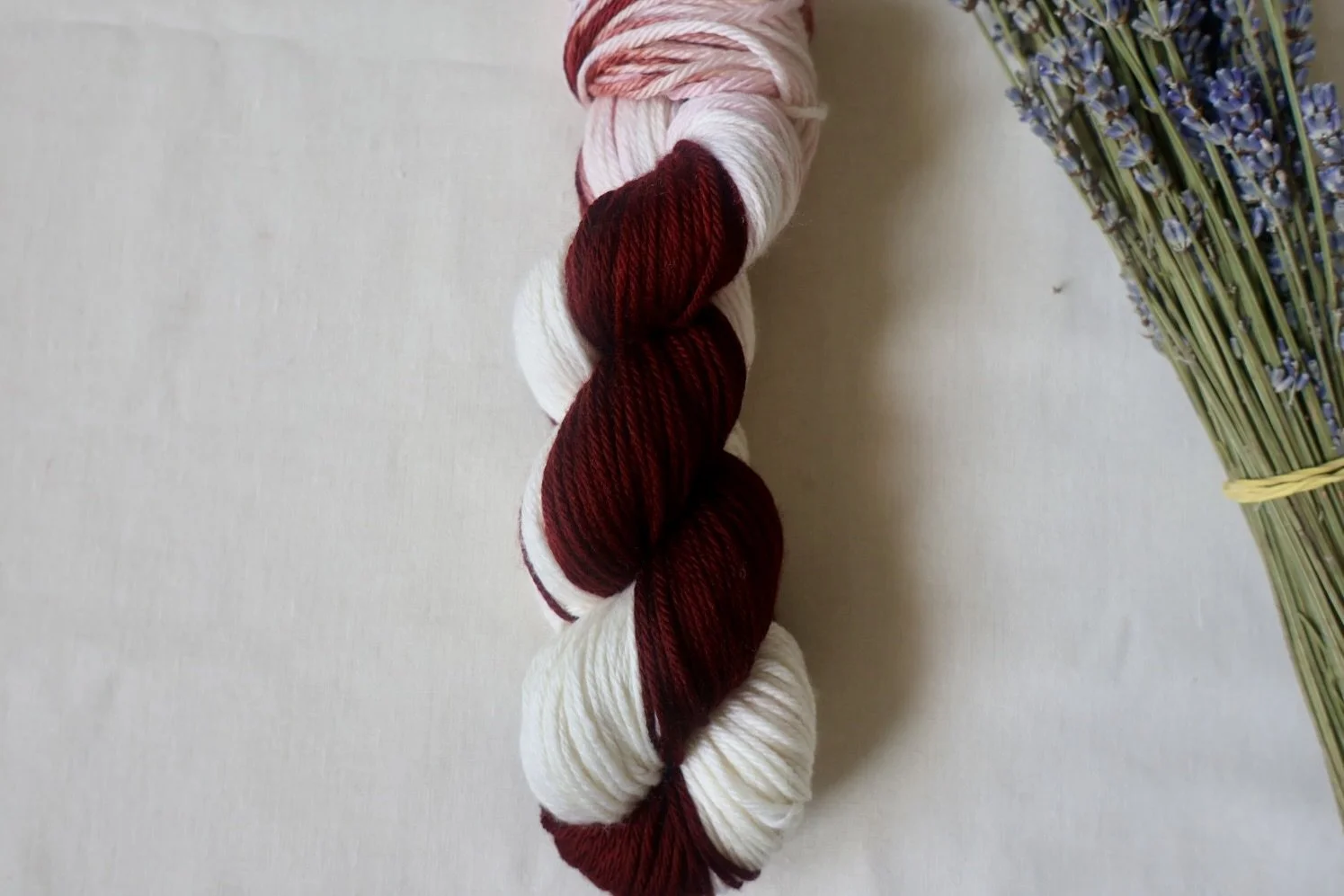 “Hand‑dyed superwash merino yarn in burgundy and cream tones”