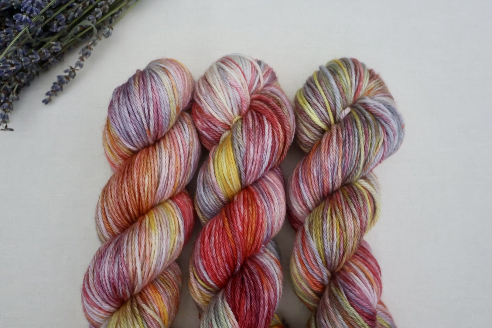 Hand‑dyed superwash merino yarn with vibrant pink, coral, yellow, and grey variegated tones, Scottish small‑batch dye