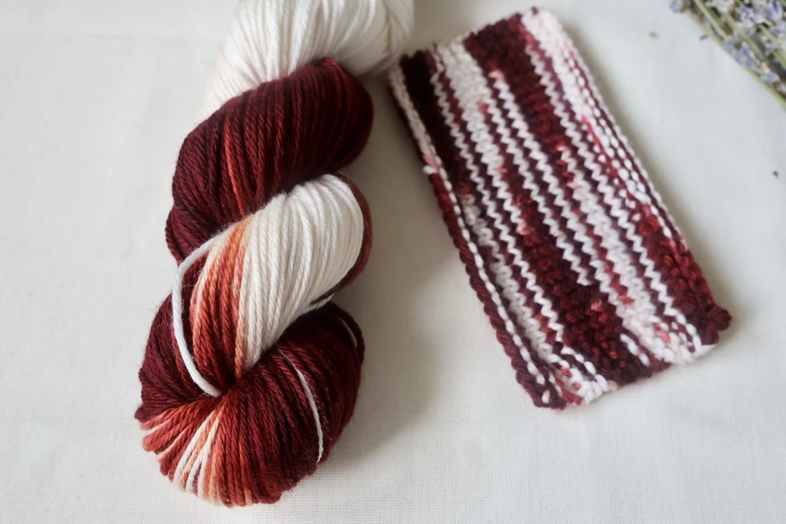 “Hand‑dyed merino yarn skeins featuring deep burgundy and soft neutral tones”