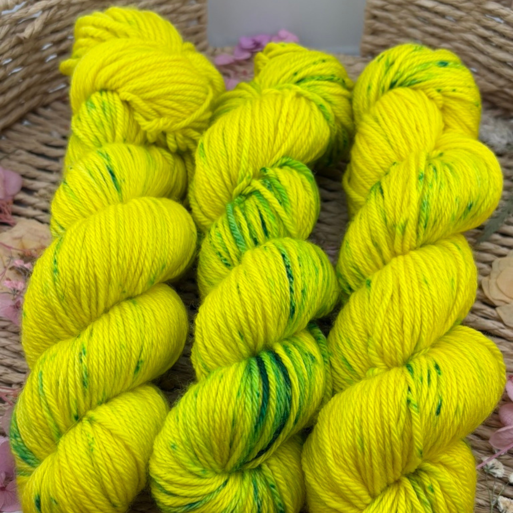 “Close‑up of vibrant yellow‑green hand‑dyed yarn skeins with subtle green speckles, highlighting fibre texture and tonal variation.”