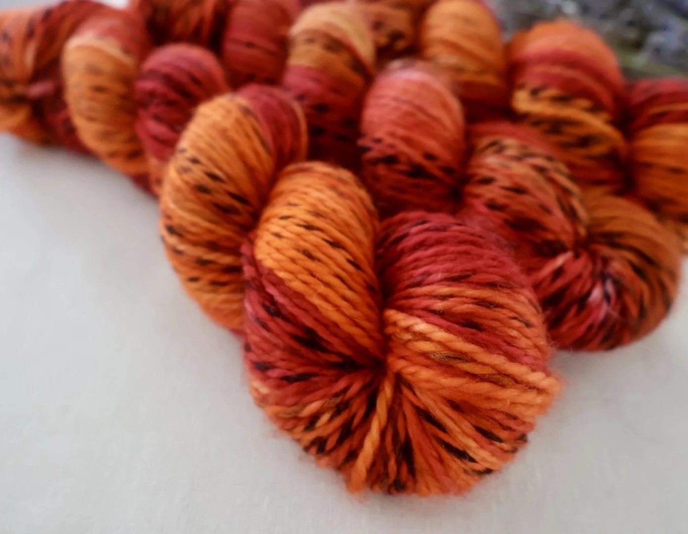 Three skeins of hand‑dyed Merino DK yarn in rich red, orange and gold hues inspired by Mary Barbour.
