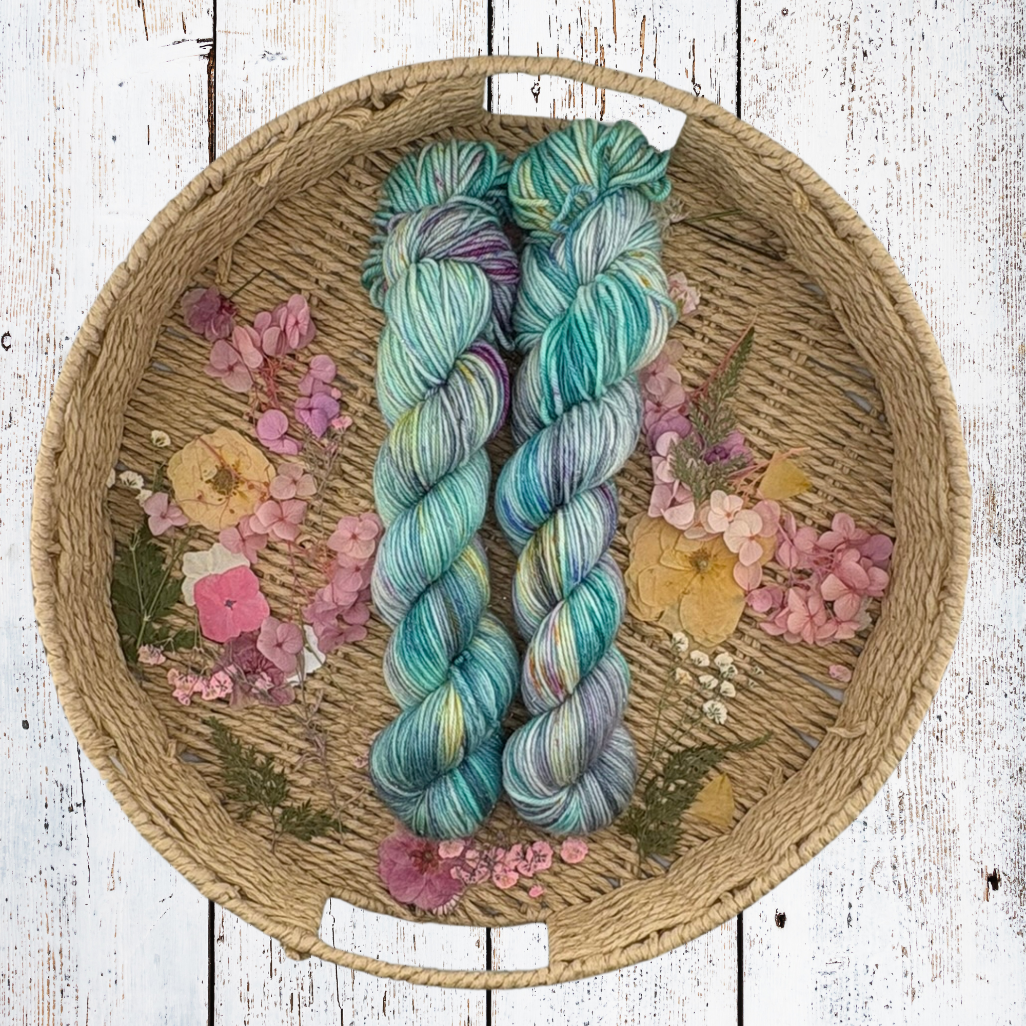 Multicolour teal and blue yarn skeins in a basket, showing soft fibre texture and coastal‑inspired colour variation
