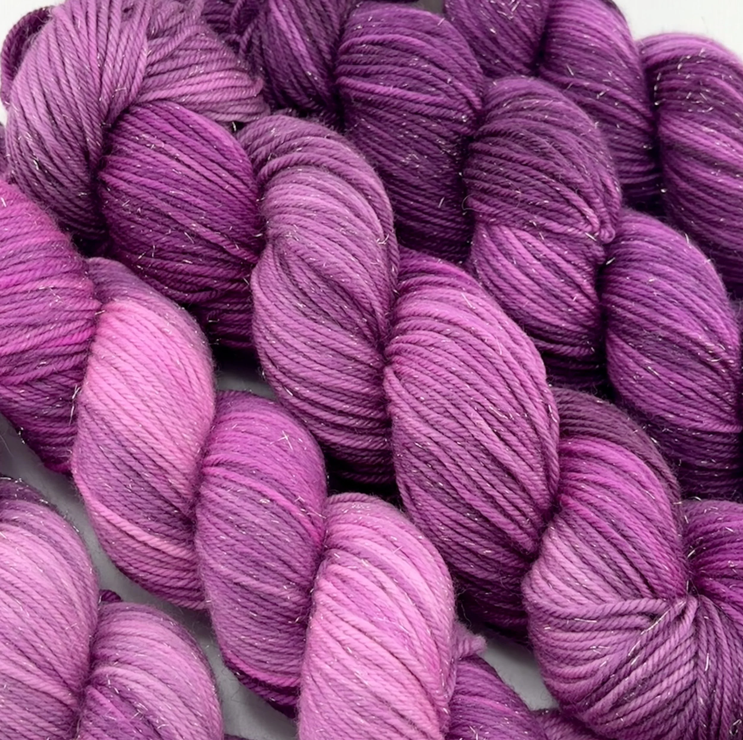 Shimmering pink and purple yarn in tonal gradients, grouped in a neat arrangement