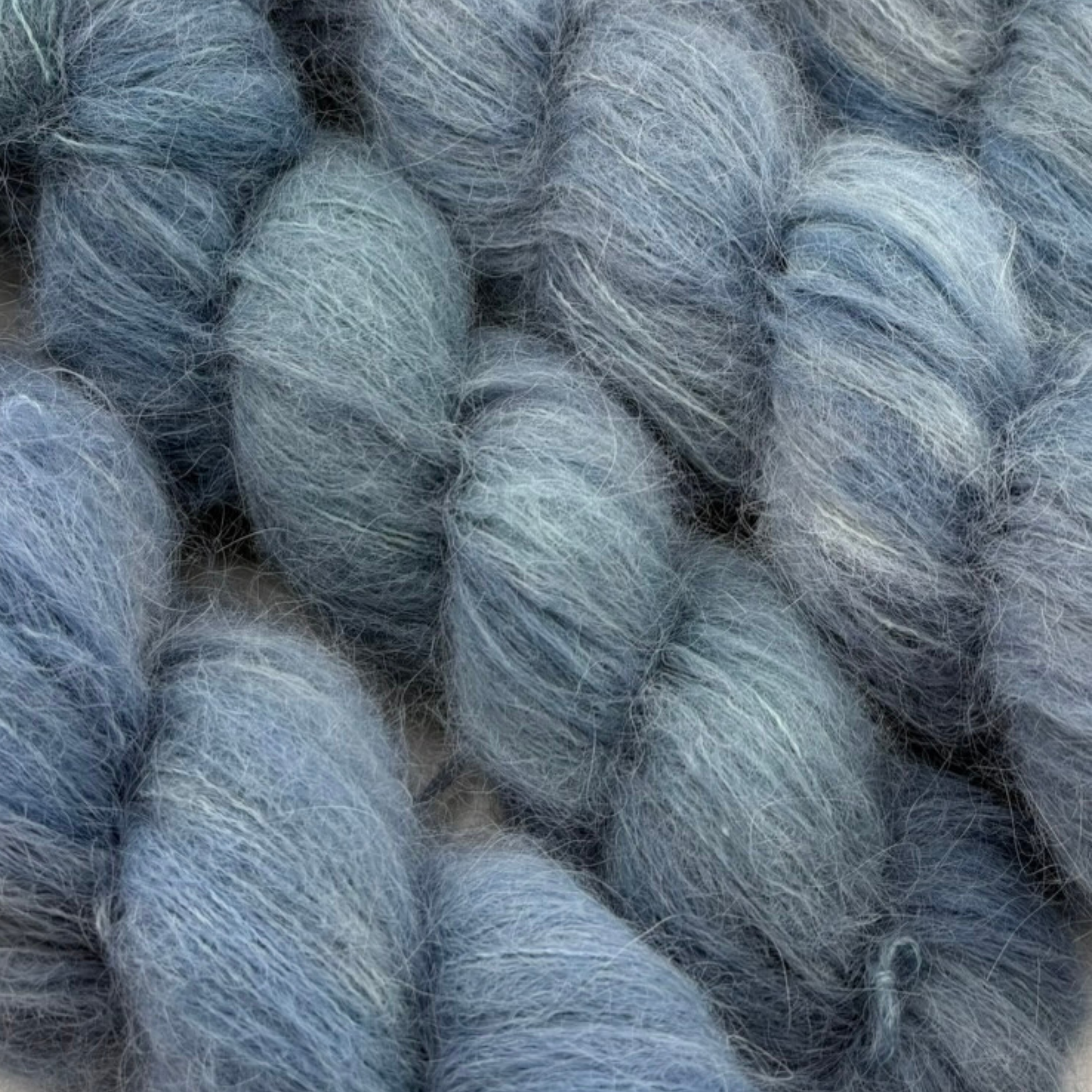 Hand‑dyed alpaca yarn in blue‑grey hues with a delicate halo, ideal for shawls, lacework, and soft accessories