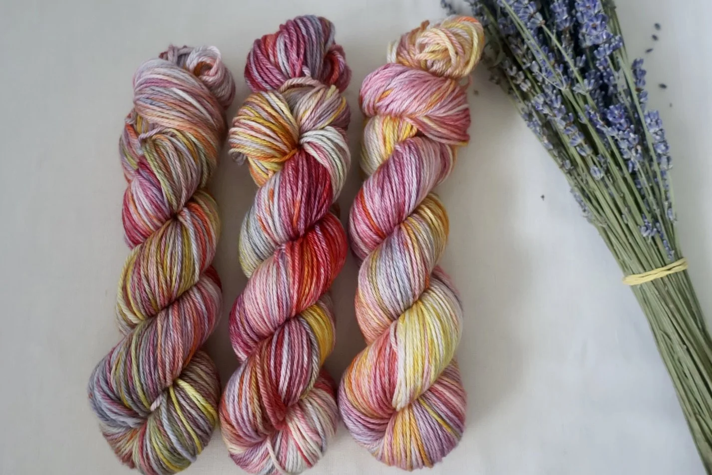 Hand‑dyed superwash merino yarn in multicoloured pink, red, yellow, and grey tones, dyed in Scotland