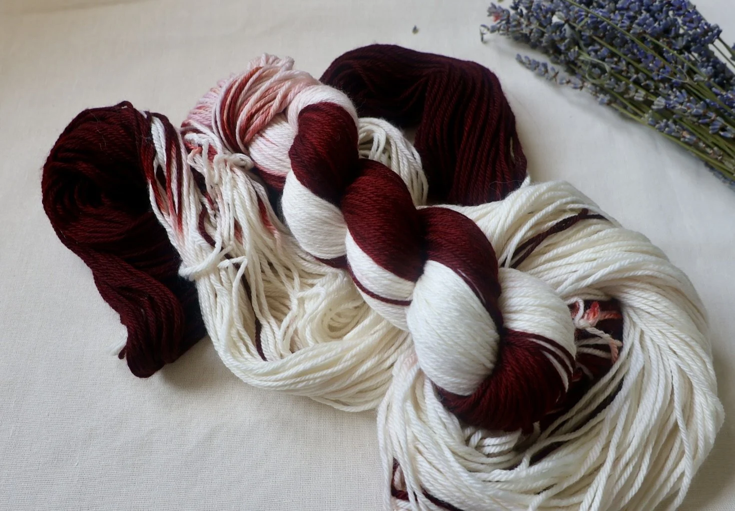 “100% superwash merino wool skein in burgundy, and cream hand‑dyed shades”