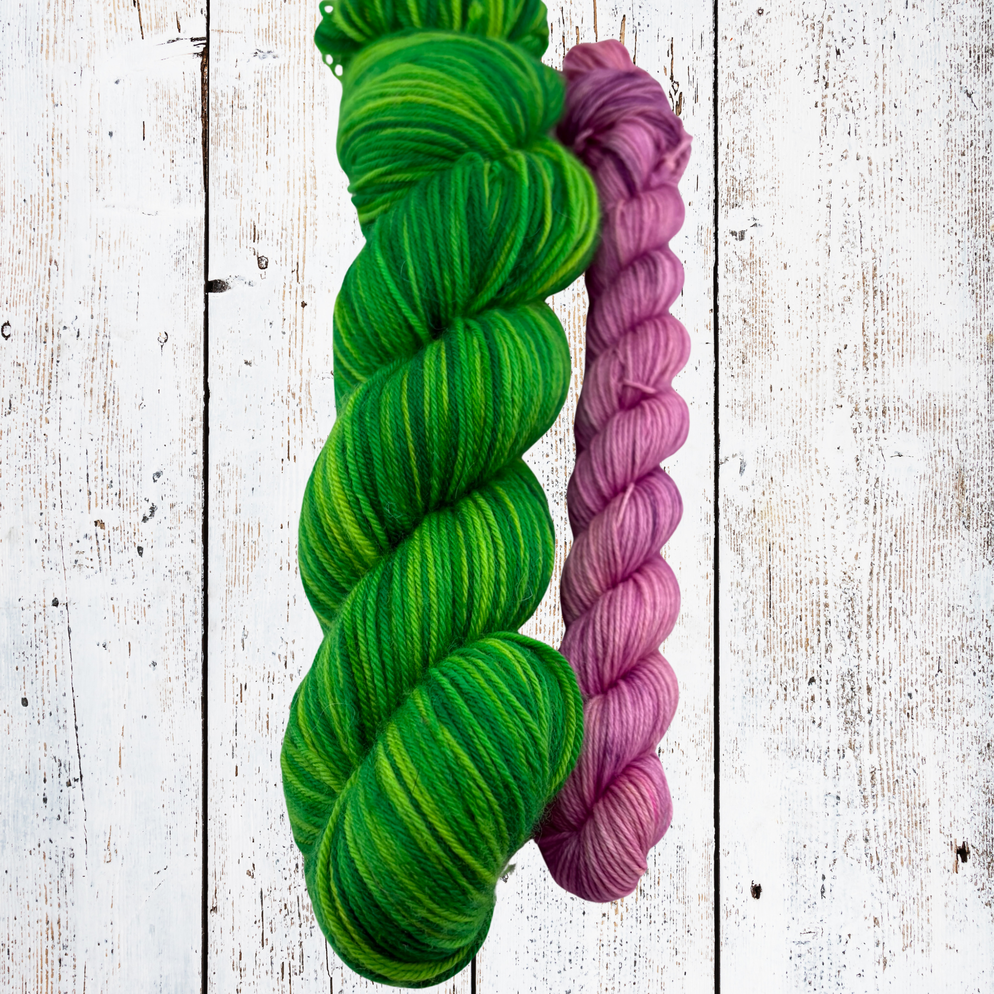 Loose strands of green, yellow and purple yarn arranged on a woven surface, showing colour blending and fibre detail.