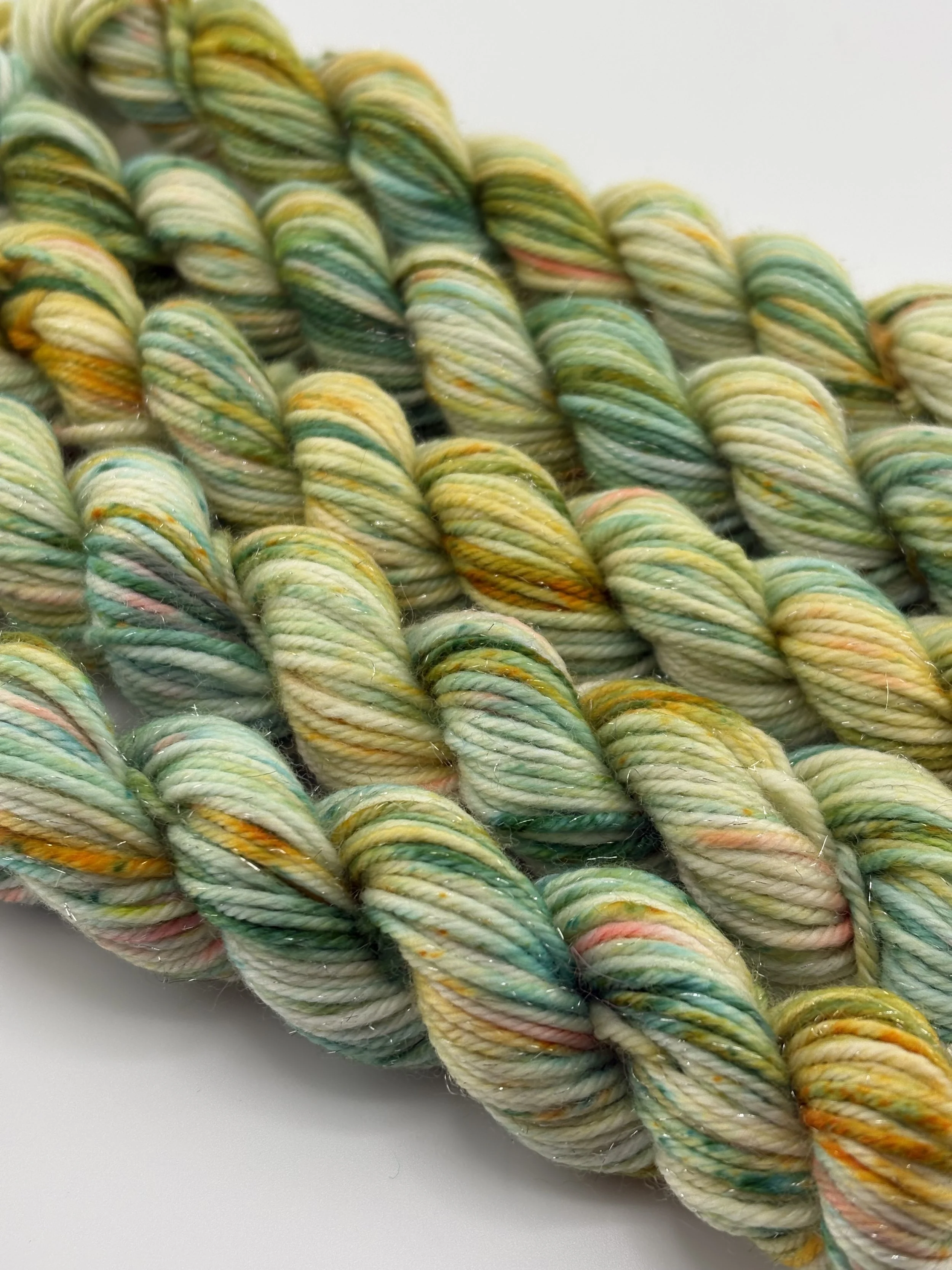 Close-up of multicolored twisted yarn skeins in pastel hues of yellow, green, pink, and orange.