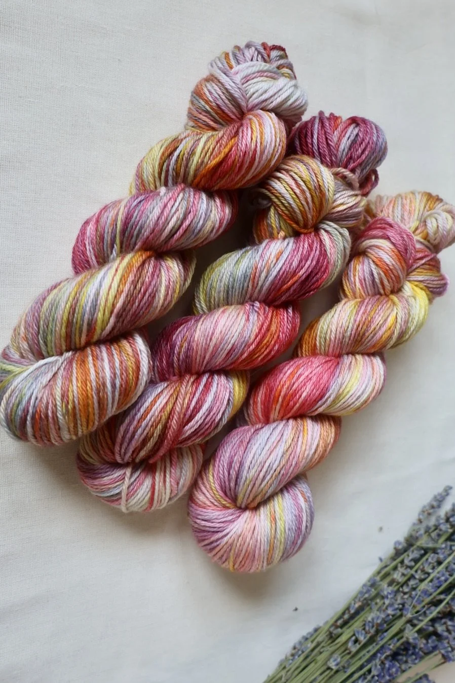 Hand‑dyed superwash merino wool with bright pink, orange, yellow, and soft grey colour variation
