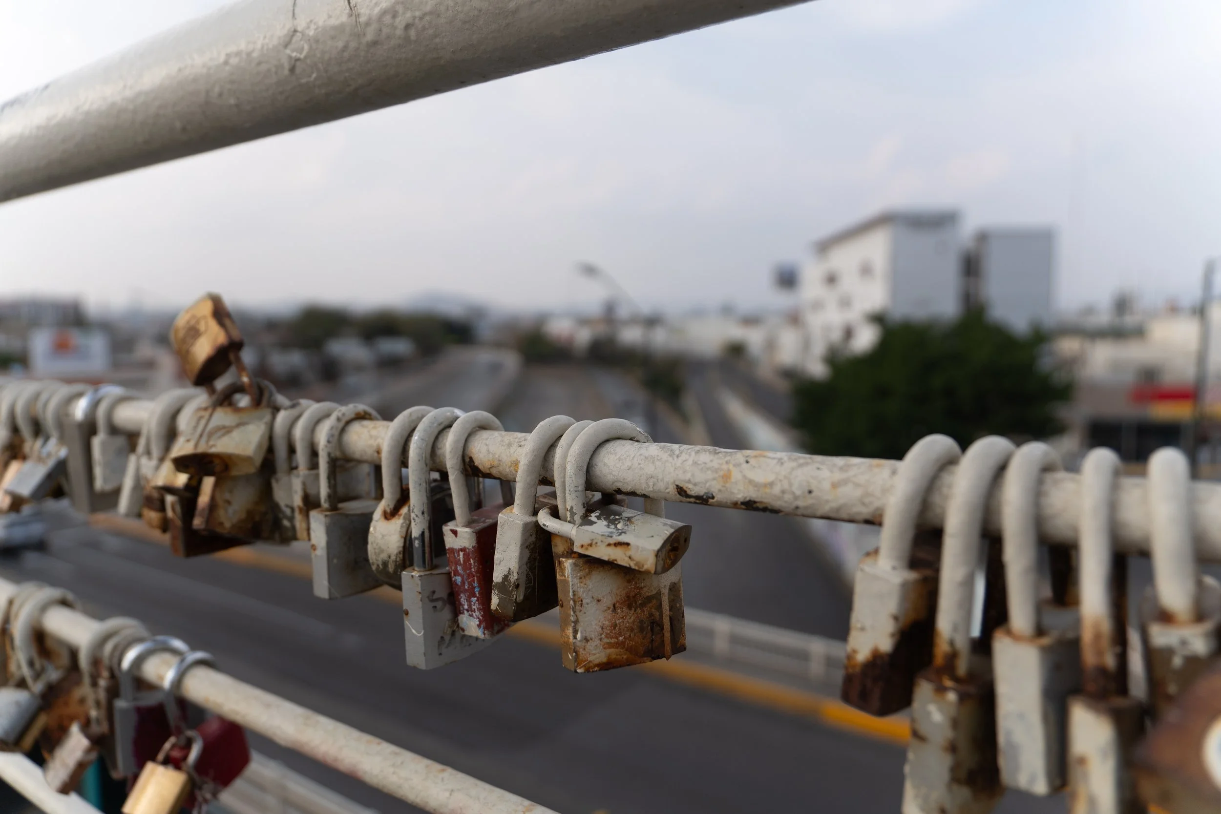 Candados en un puente con un fondo citadino. (c) 2026 Héctor Obregón
