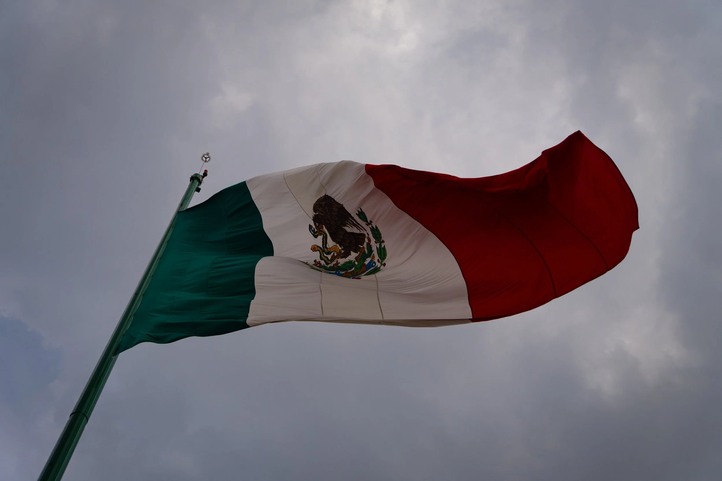 Bandera de México ondeando en el viento con fondo nublado. (c) 2026 Héctor Obregón